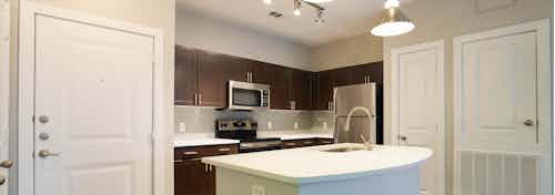 Redesigned kitchen at AMLI Inverness apartments with espresso cabinets and white granite counter tops and overhead lighting