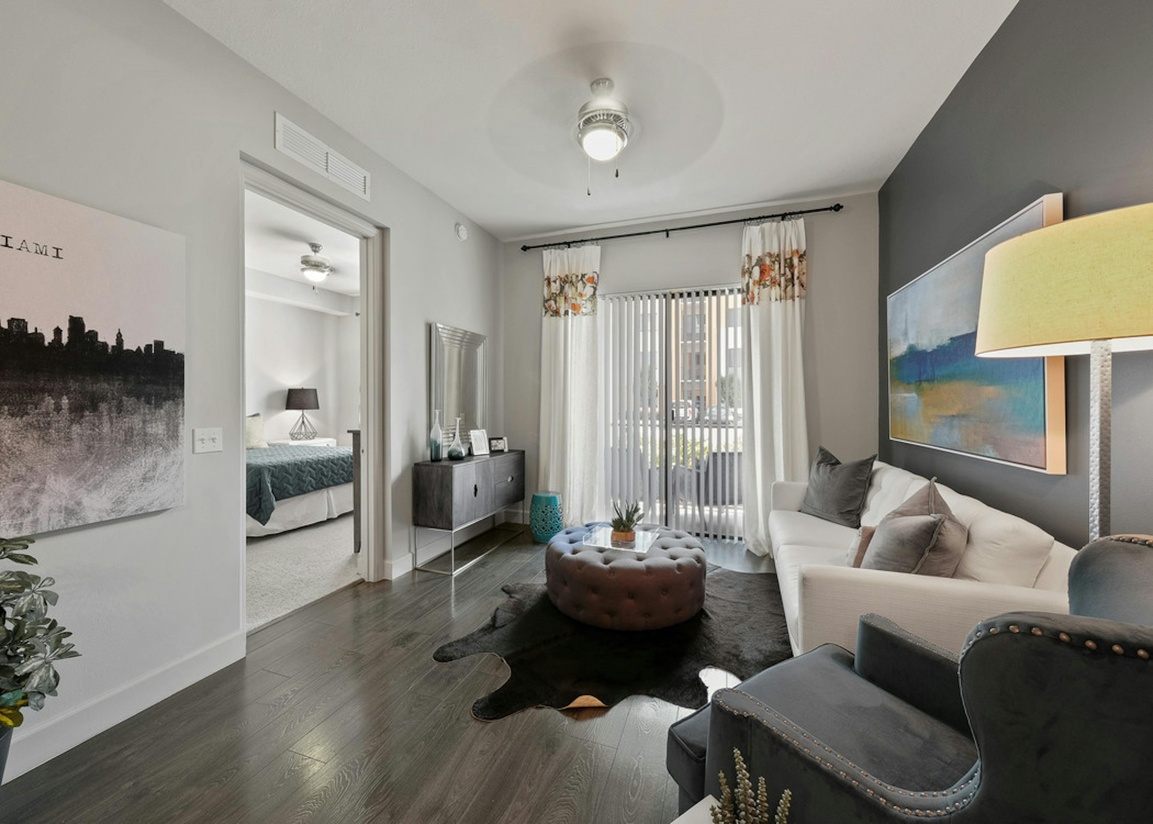 AMLI 8800 apartment living area with white sofa and artwork, toss pillows and view from the sliding patio door