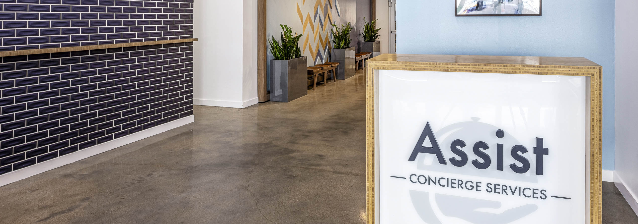 AMLI on 2nd concierge desk with large assist sign in front of light blue wall and across from blue tile wall on concrete floor