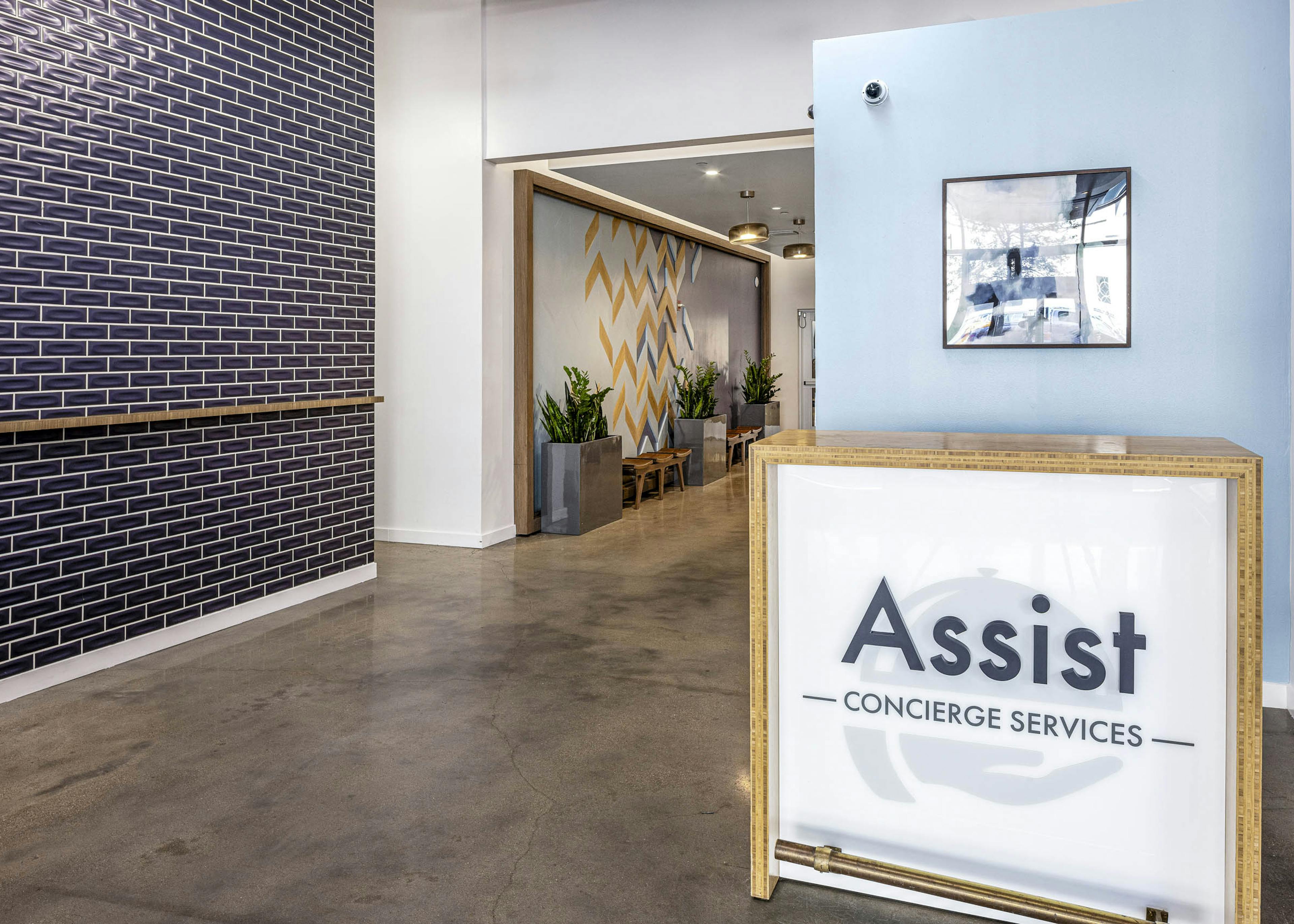 AMLI on 2nd concierge desk with large assist sign in front of light blue wall and across from blue tile wall on concrete floor