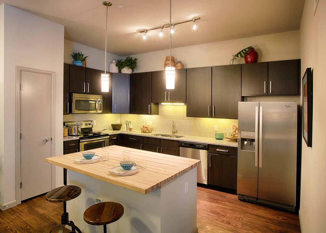A kitchen at AMLI Denargo Market apartments with an island and a stainless steel fridge and several cabinets and a closet