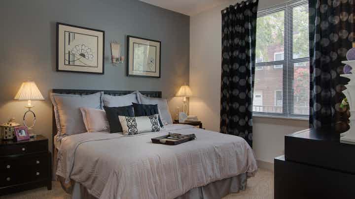 Interior of AMLI Old 4th Ward bedroom with cream walls and high ceilings with carpet and large window for natural sunlight
