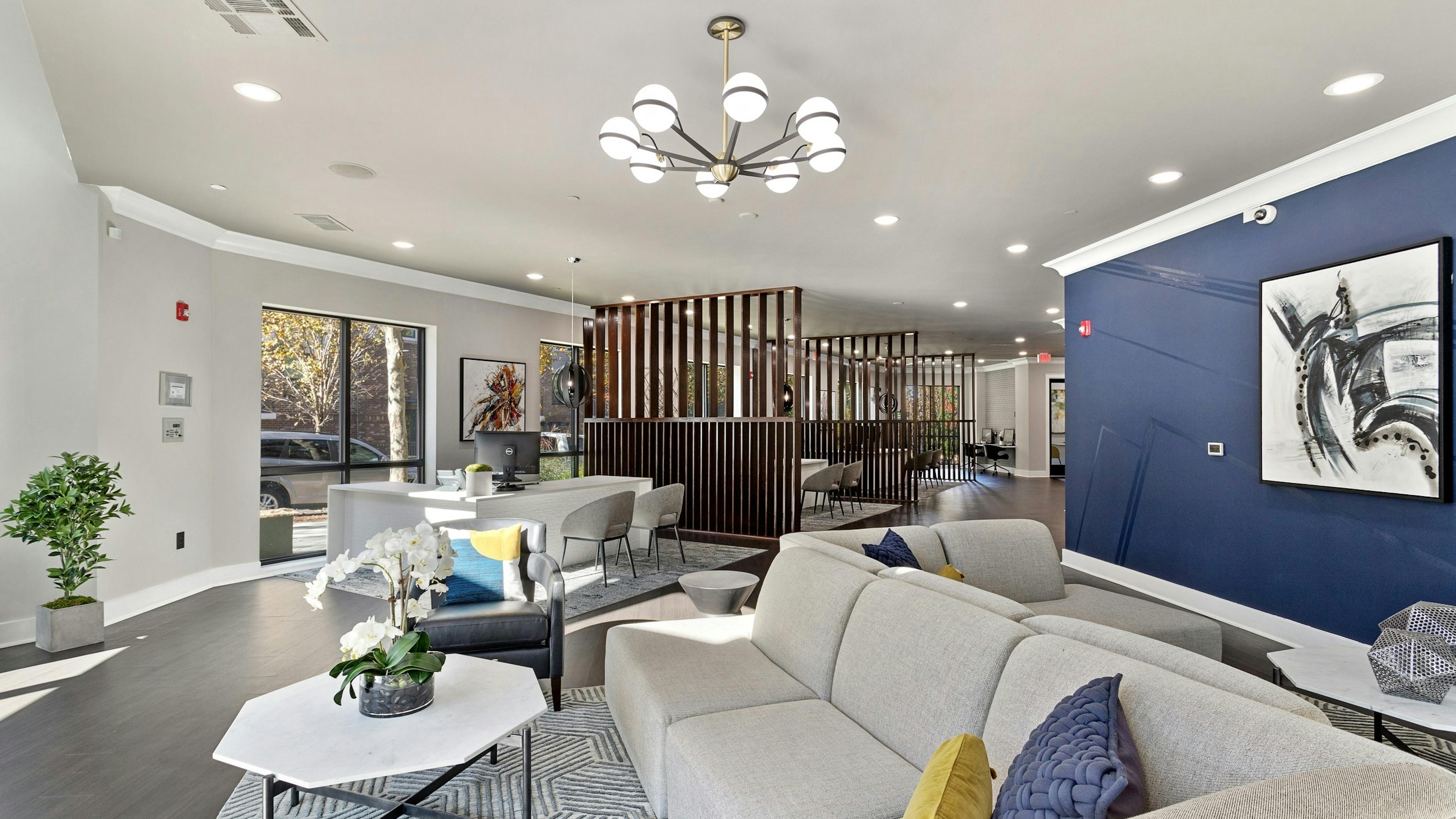 Interior view of the AMLI Parkside leasing office with front desk and modern seating area with chandelier and blue accent wall