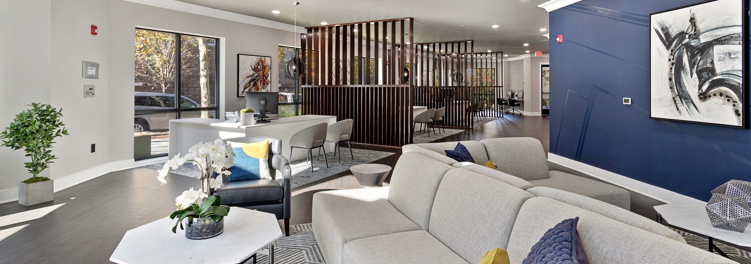 Interior view of the AMLI Parkside leasing office with front desk and modern seating area with chandelier and blue accent wall
