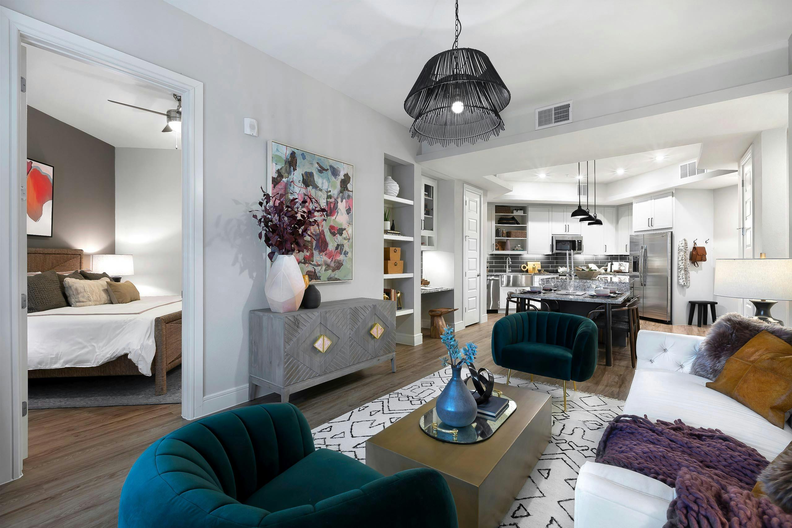 AMLI Lakeline apartment living room with plush seating on white geometric carpet and view of kitchen with black backsplash