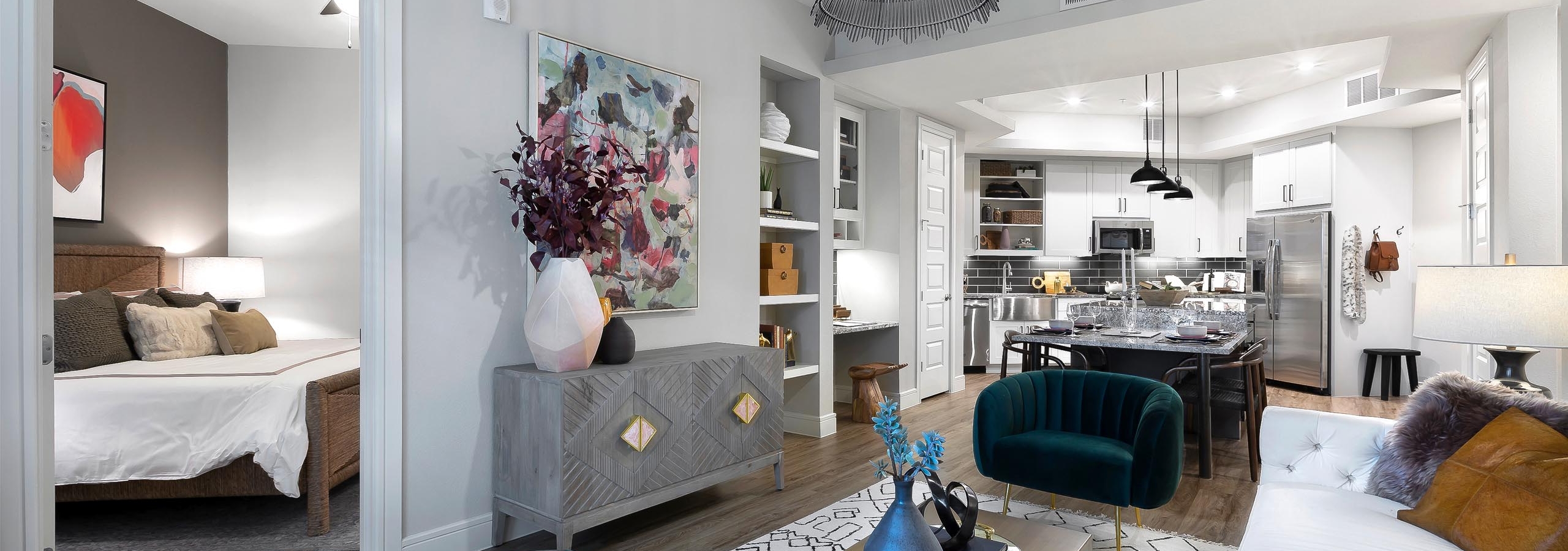 AMLI Lakeline apartment living room with plush seating on white geometric carpet and view of kitchen with black backsplash
