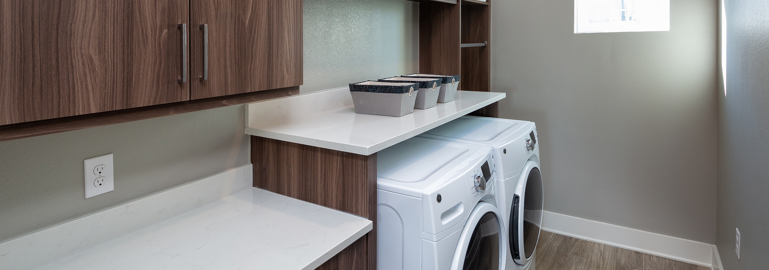 Interior view of AMLI South Shore in unit washer and dryer tucked under a raised cabinet with a white countertop