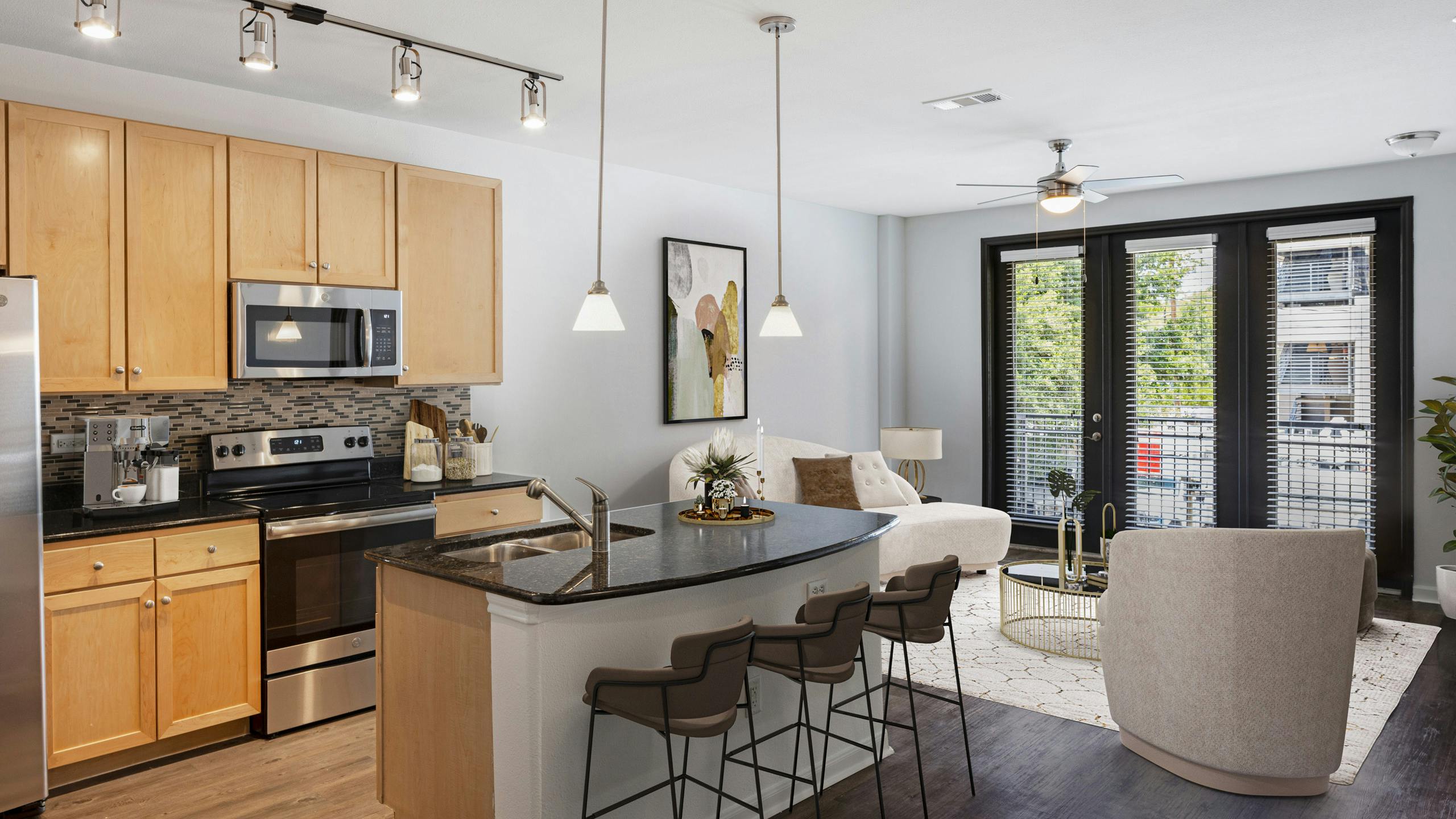 AMLI 300 apartment kitchen with light wood cabinets with black granite countertops and living room with white couch and chairs