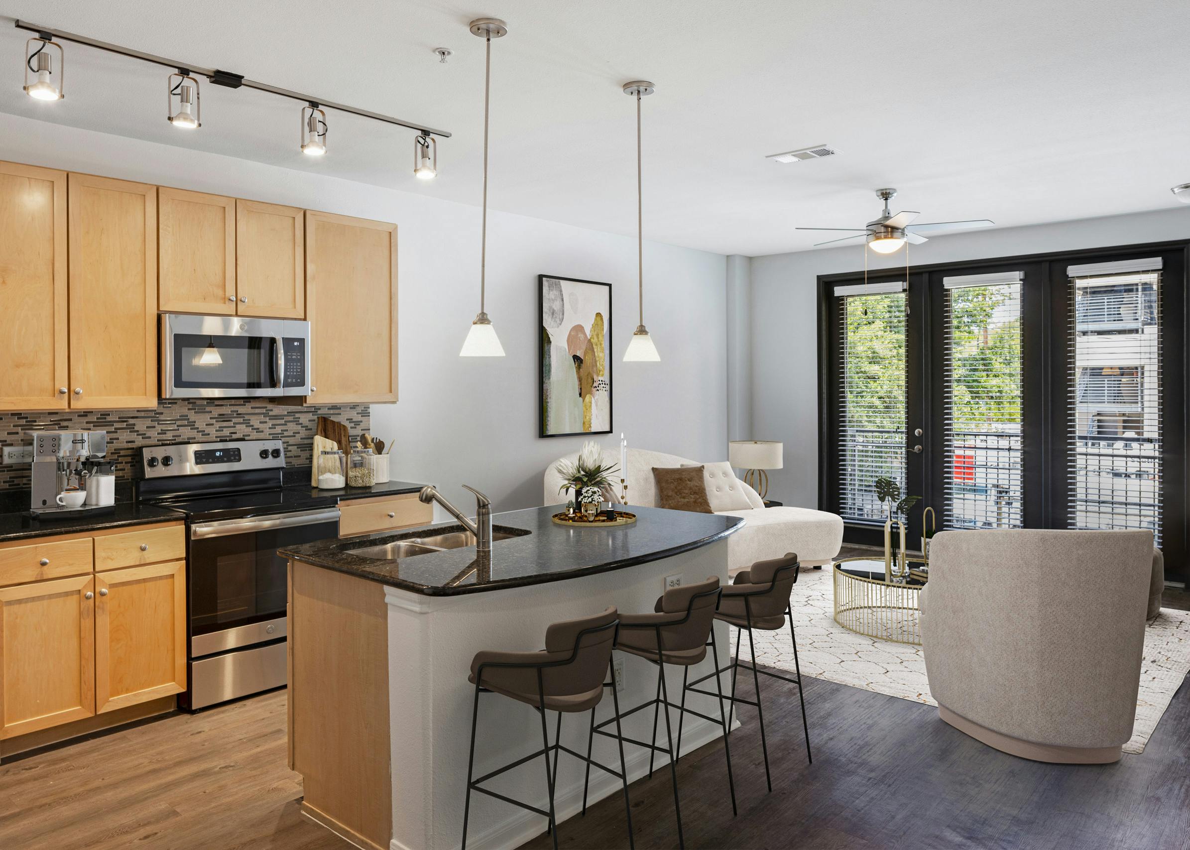 AMLI 300 apartment kitchen with light wood cabinets with black granite countertops and living room with white couch and chairs