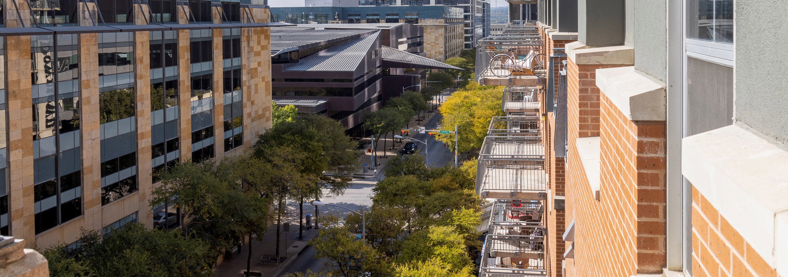 Daytime views from AMLI Downtown balconies multiple stores up with trees and Austin skyscrapers in the background