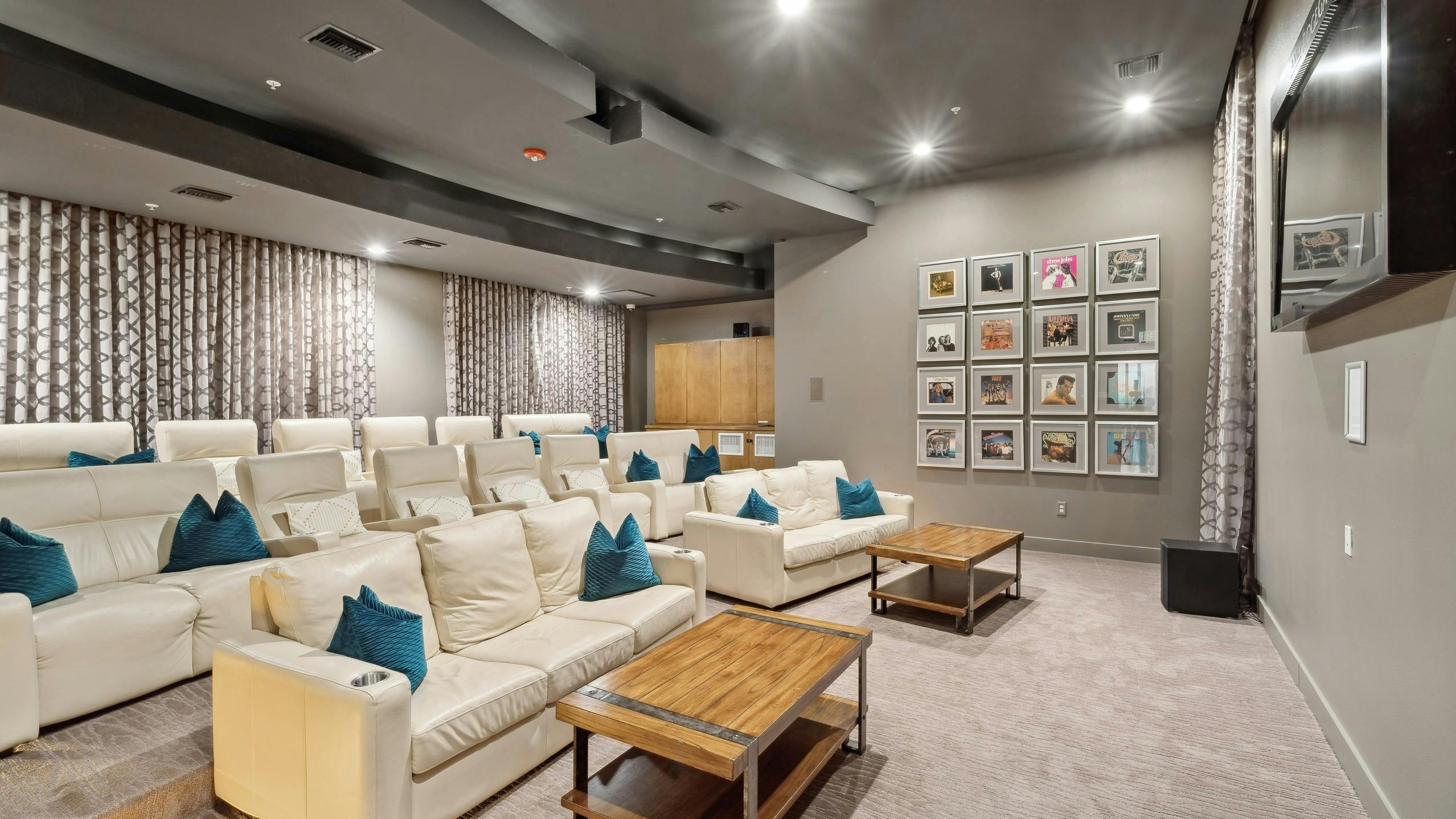 Interior view of theatre at AMLI RidgeGate with a large TV and couches and coffee tables and record albums on the wall