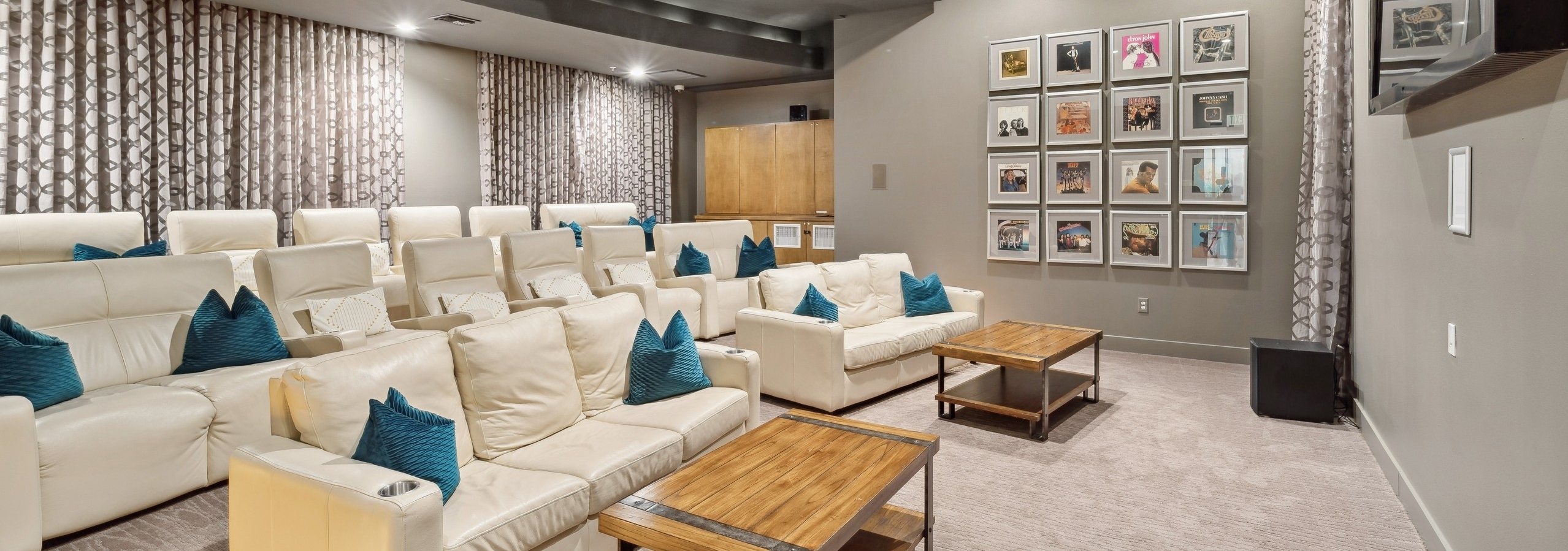 Interior view of theatre at AMLI RidgeGate with a large TV and couches and coffee tables and record albums on the wall