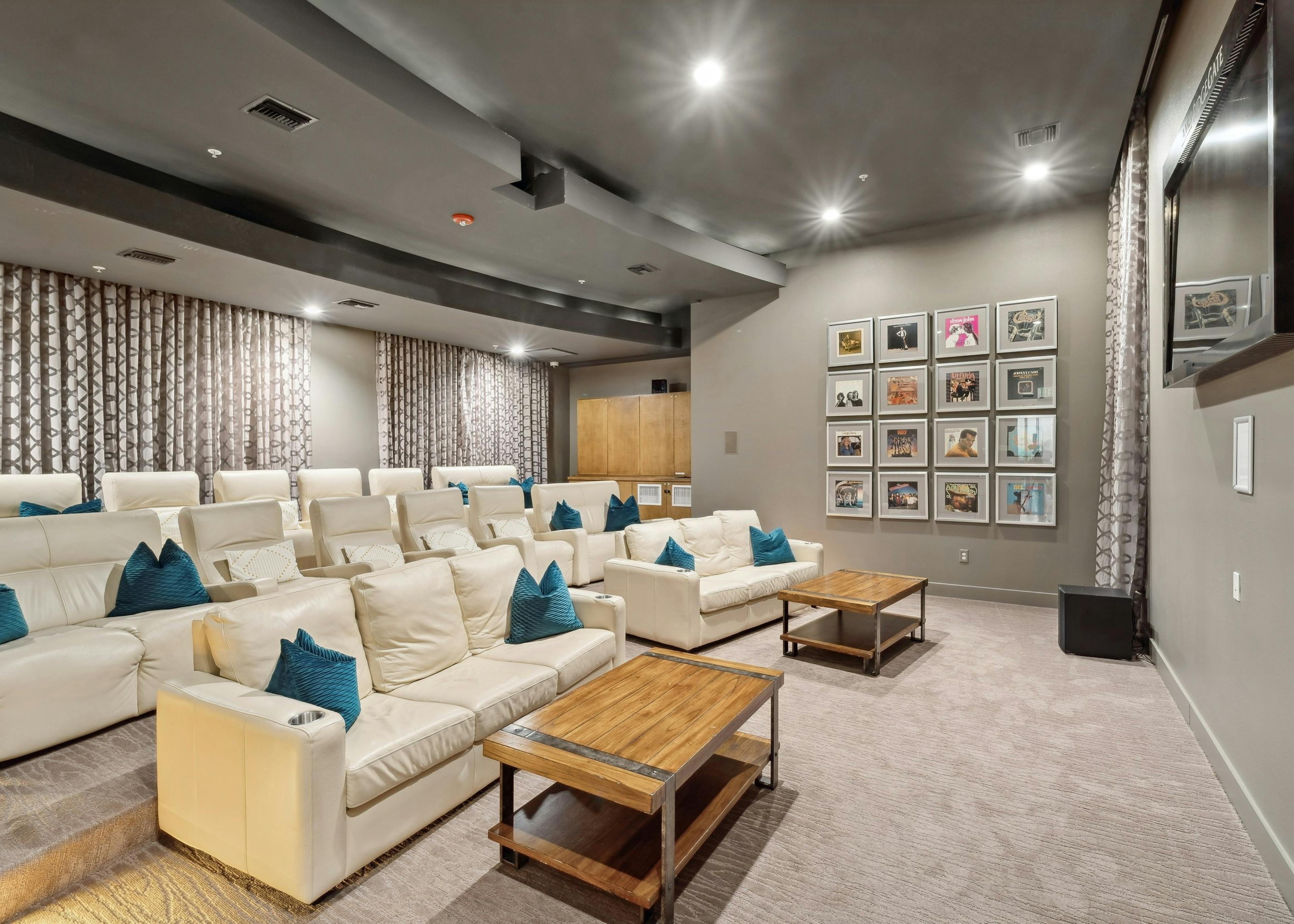 Interior view of theatre at AMLI RidgeGate with a large TV and couches and coffee tables and record albums on the wall