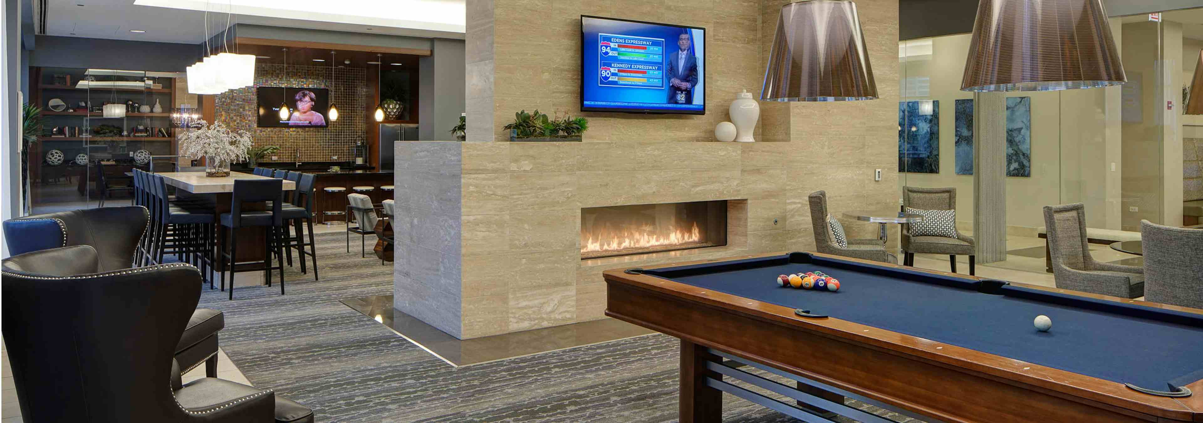 Clubroom at AMLI River North with billiards and a large fireplace as well as a flat screen TV and multiple seating options