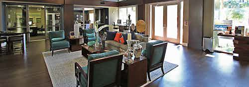 Interior daytime view of AMLI Warner Center leasing office with 2 glass wall offices, stylish lounge seating and java bar