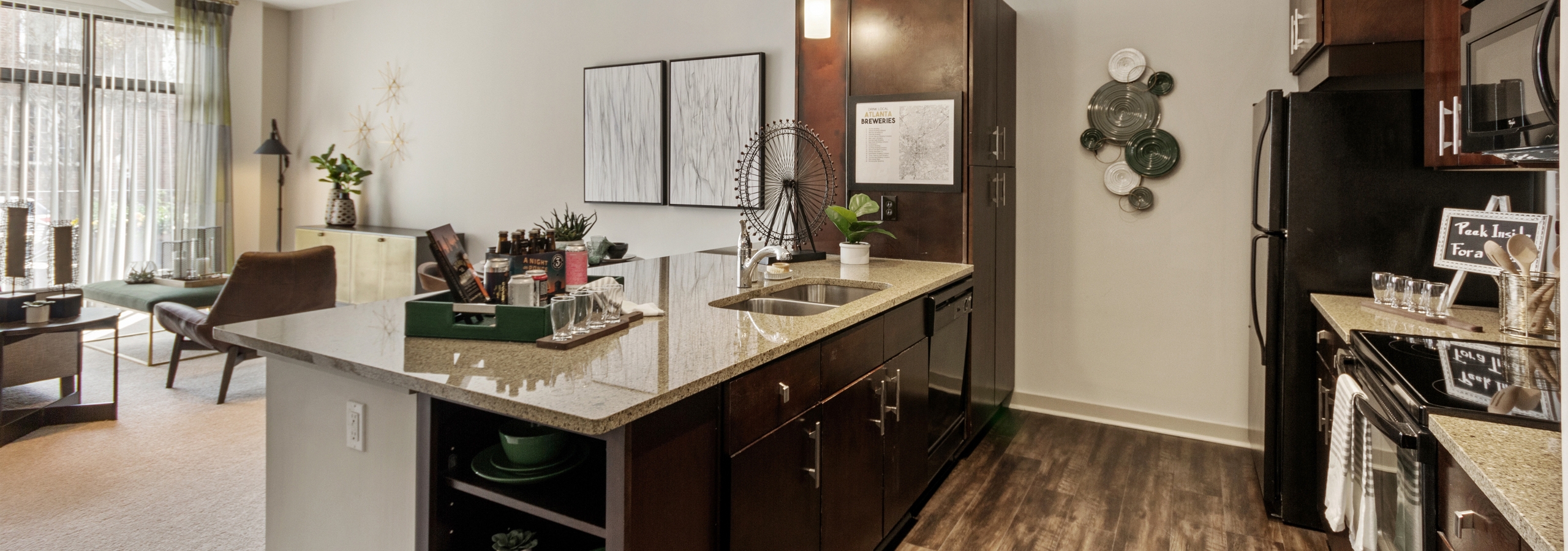 AMLI Old 4th Ward renovated kitchen with light granite countertops and dark cabinetry with black appliances and wood floors