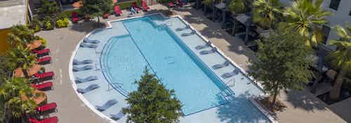 Aerial view of landscaped swimming pool at AMLI on Aldrich with colorful blocks on one end and red lounge chairs and cabanas