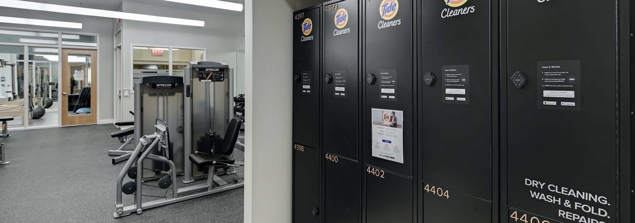 Close up of Tide Cleaners lockers in the AMLI Evanston fitness center with view of exercise machines in the background