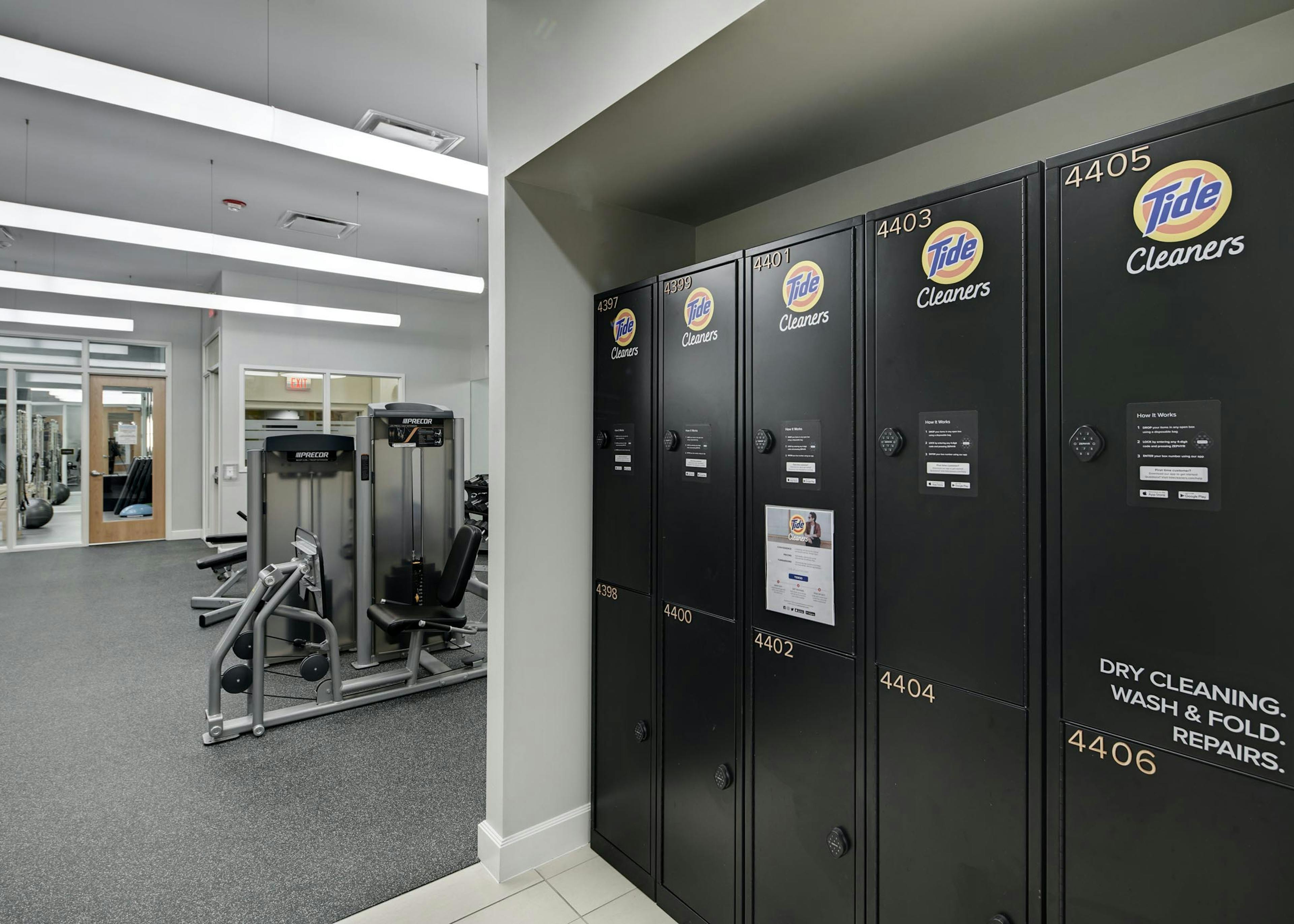 Close up of Tide Cleaners lockers in the AMLI Evanston fitness center with view of exercise machines in the background