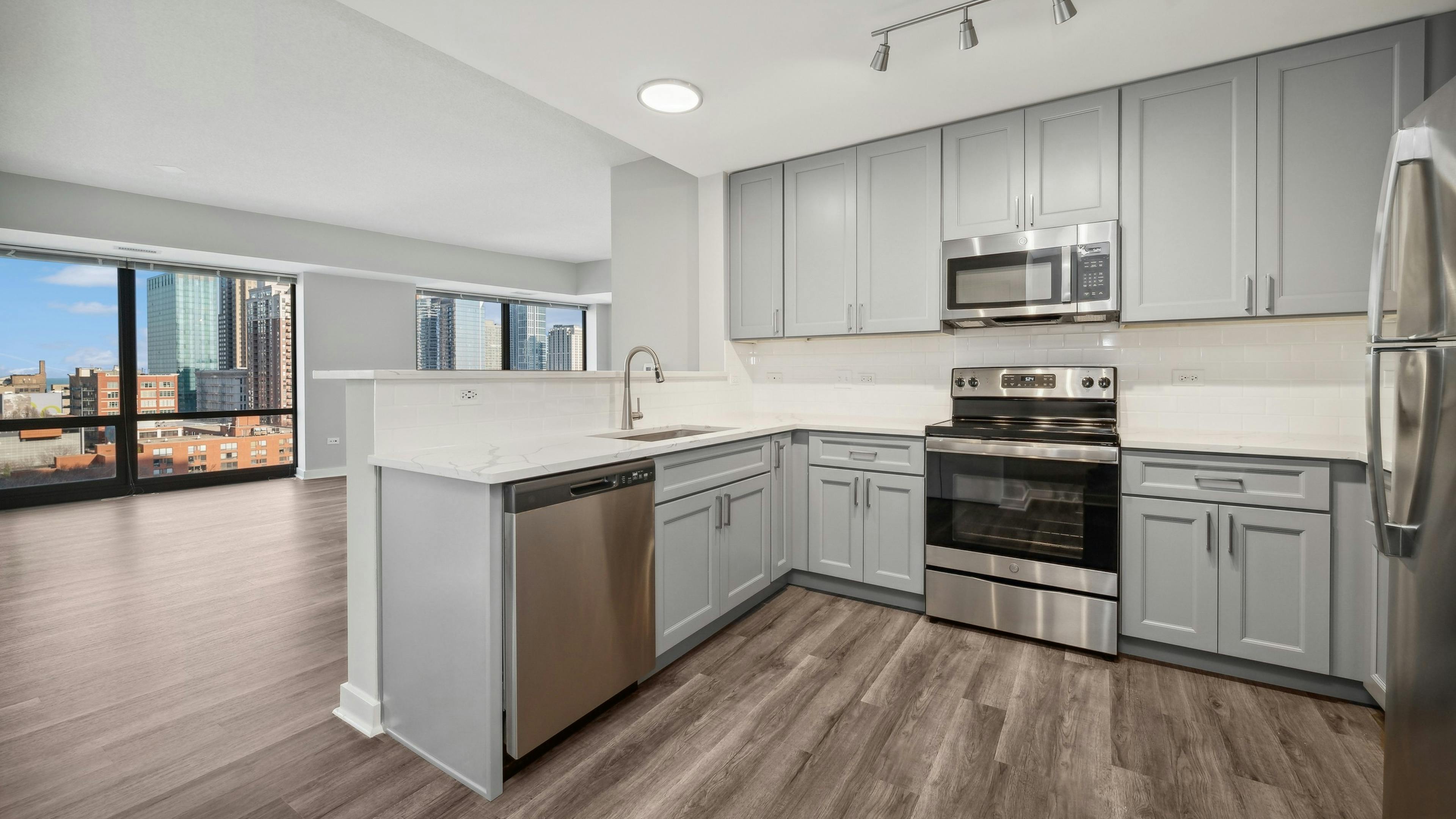 AMLI 900 apartment kitchen with gray cabinets and white countertops and backsplash paired with stainless appliances