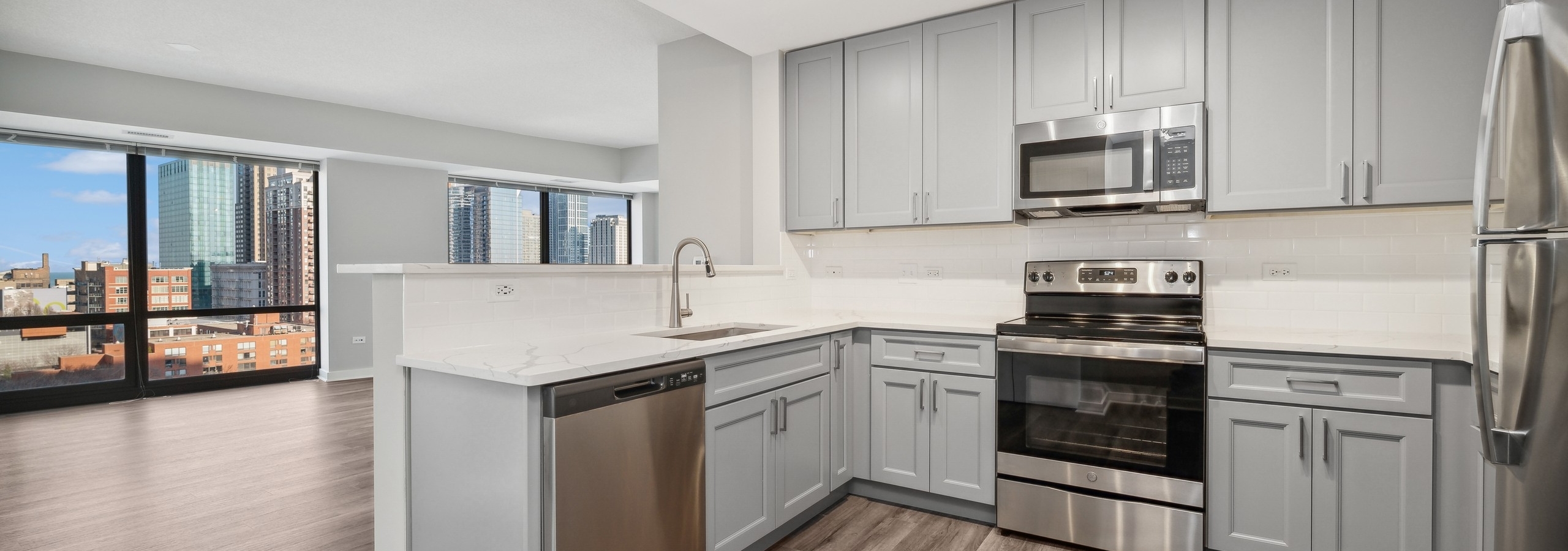 AMLI 900 apartment kitchen with gray cabinets and white countertops and backsplash paired with stainless appliances