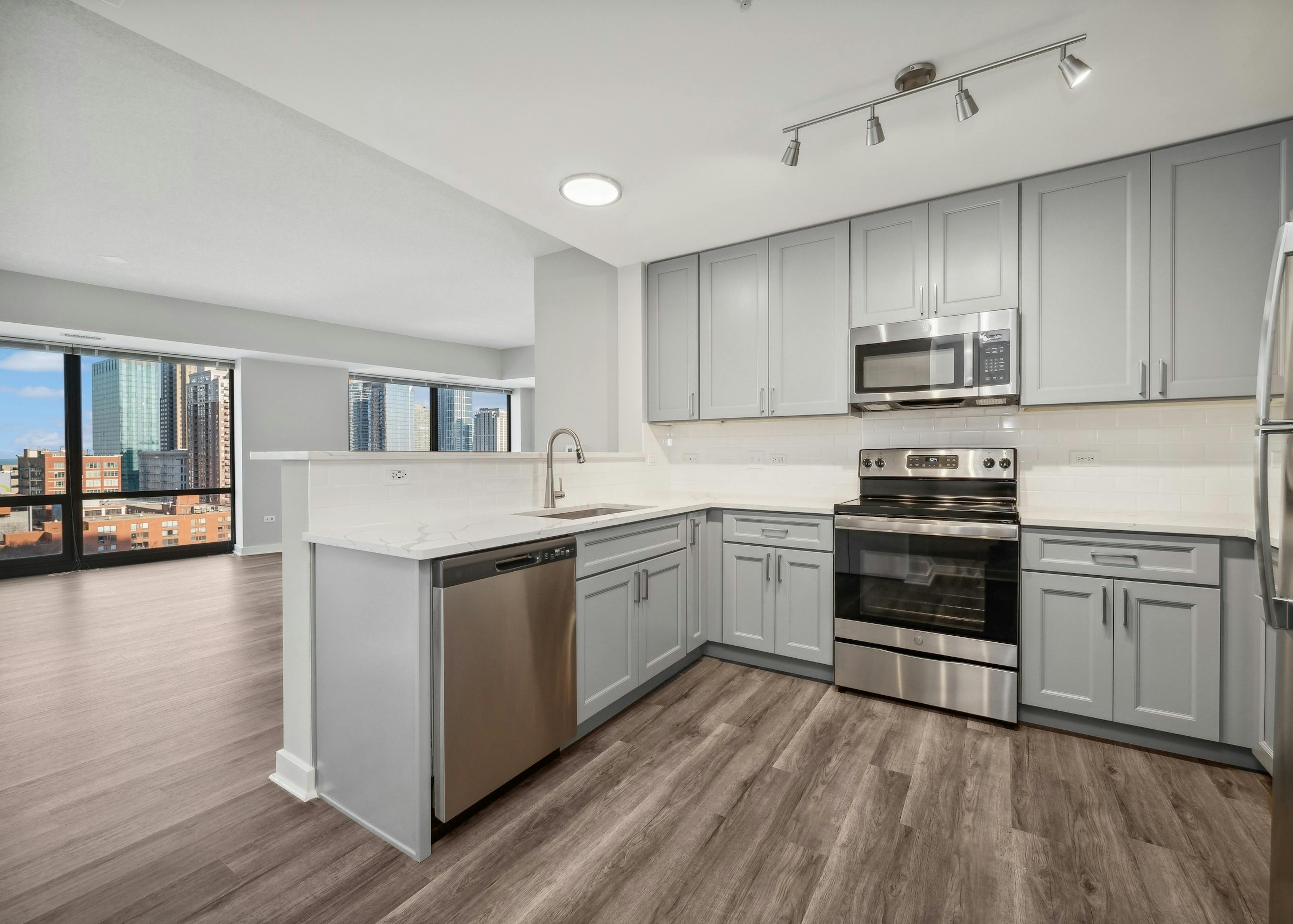 AMLI 900 apartment kitchen with gray cabinets and white countertops and backsplash paired with stainless appliances