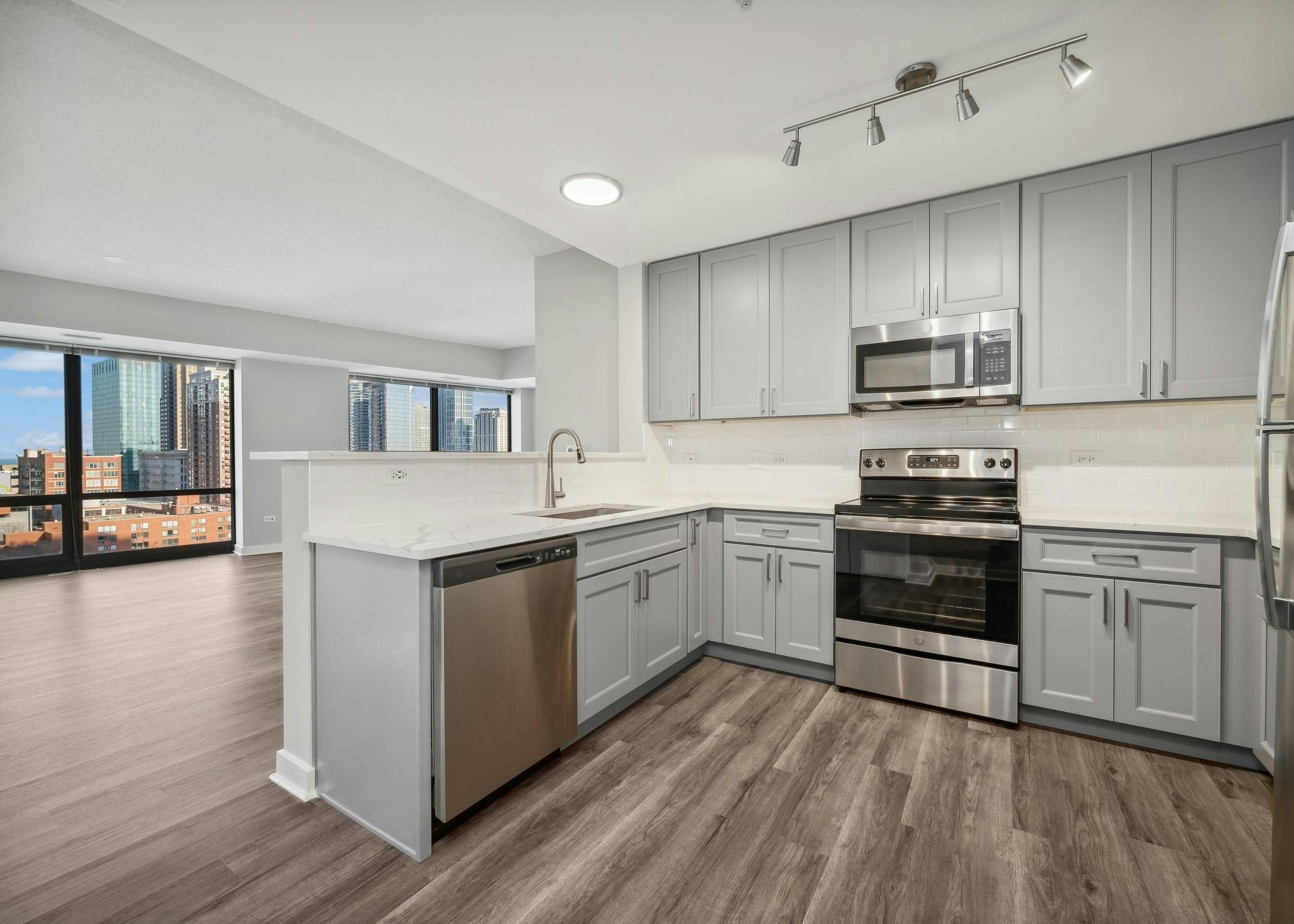 AMLI 900 apartment kitchen with gray cabinets and white countertops and backsplash paired with stainless appliances