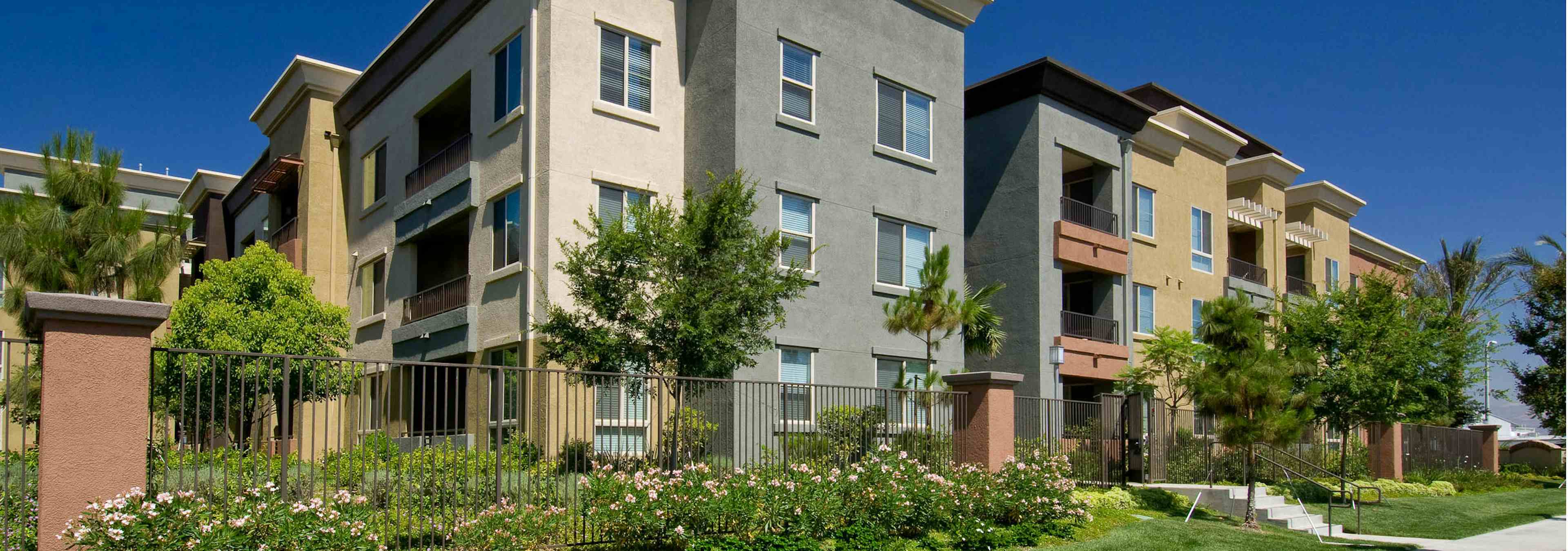 Exterior daytime landscaped rendering with surrounding trees of AMLI Warner Center apartment building and private patio views