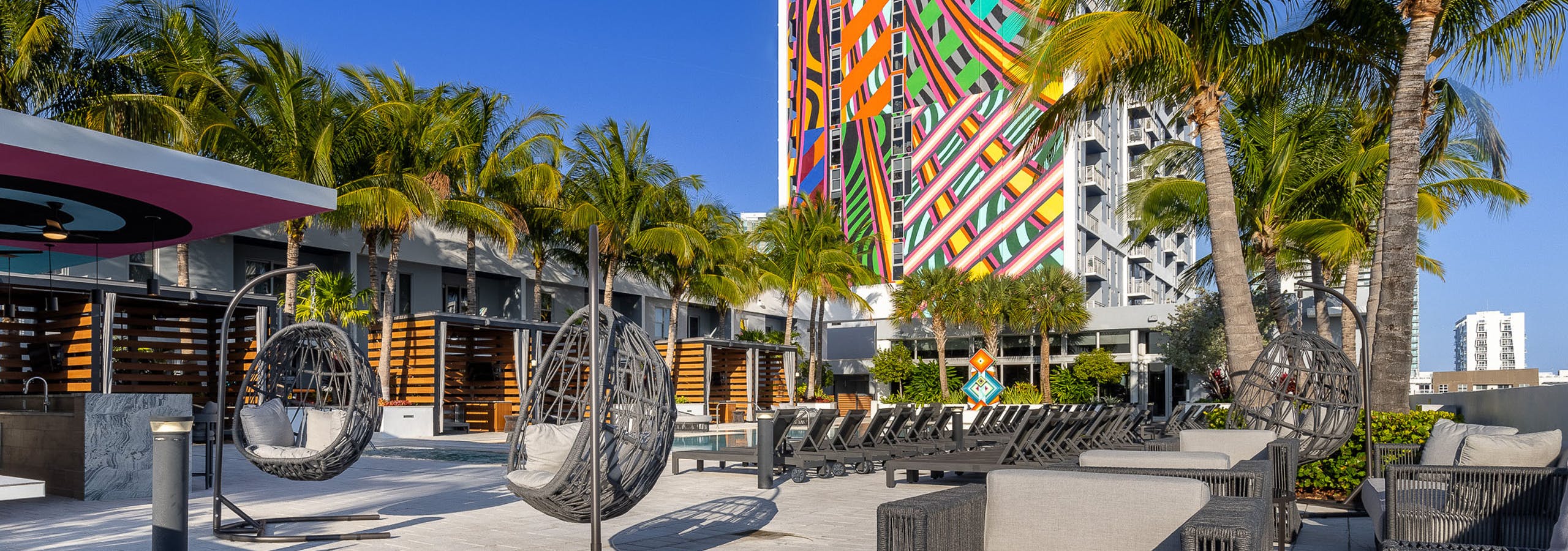 AMLI Midtown 29 apartments pool deck with various seating and palm trees and colorful building mural in rear