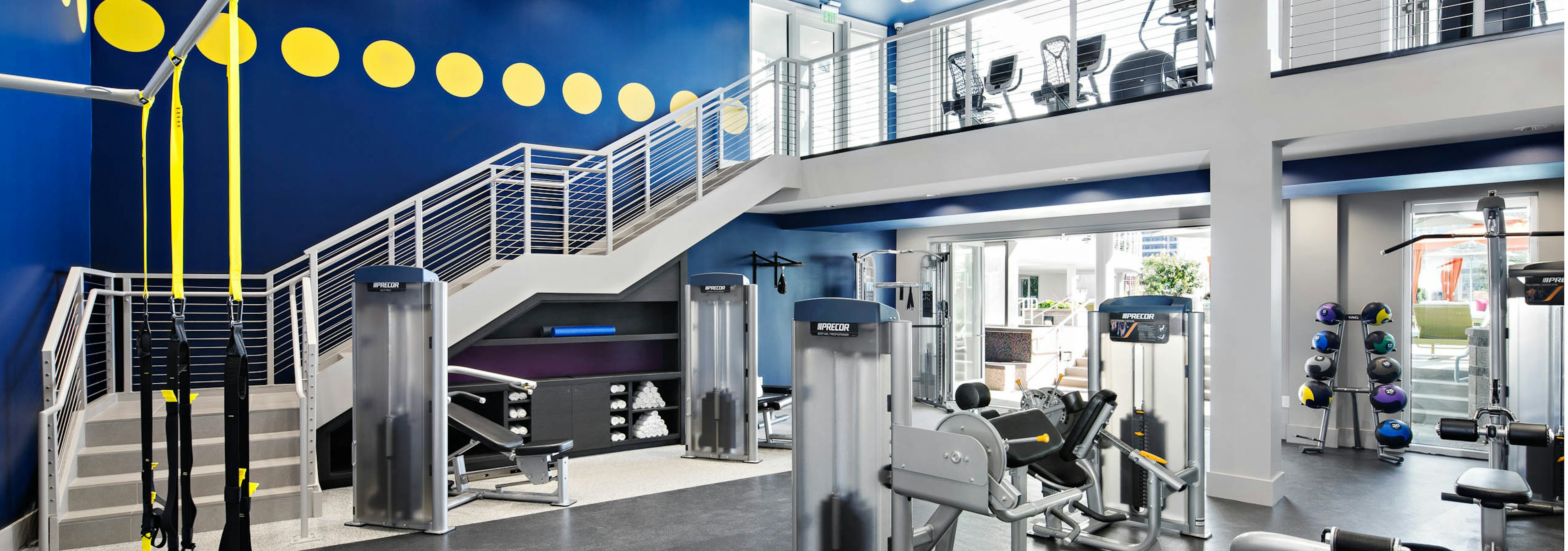 Interior of two-story fitness center at AMLI Lex on Orange apartments with TRX system and medicine balls and cardio machines