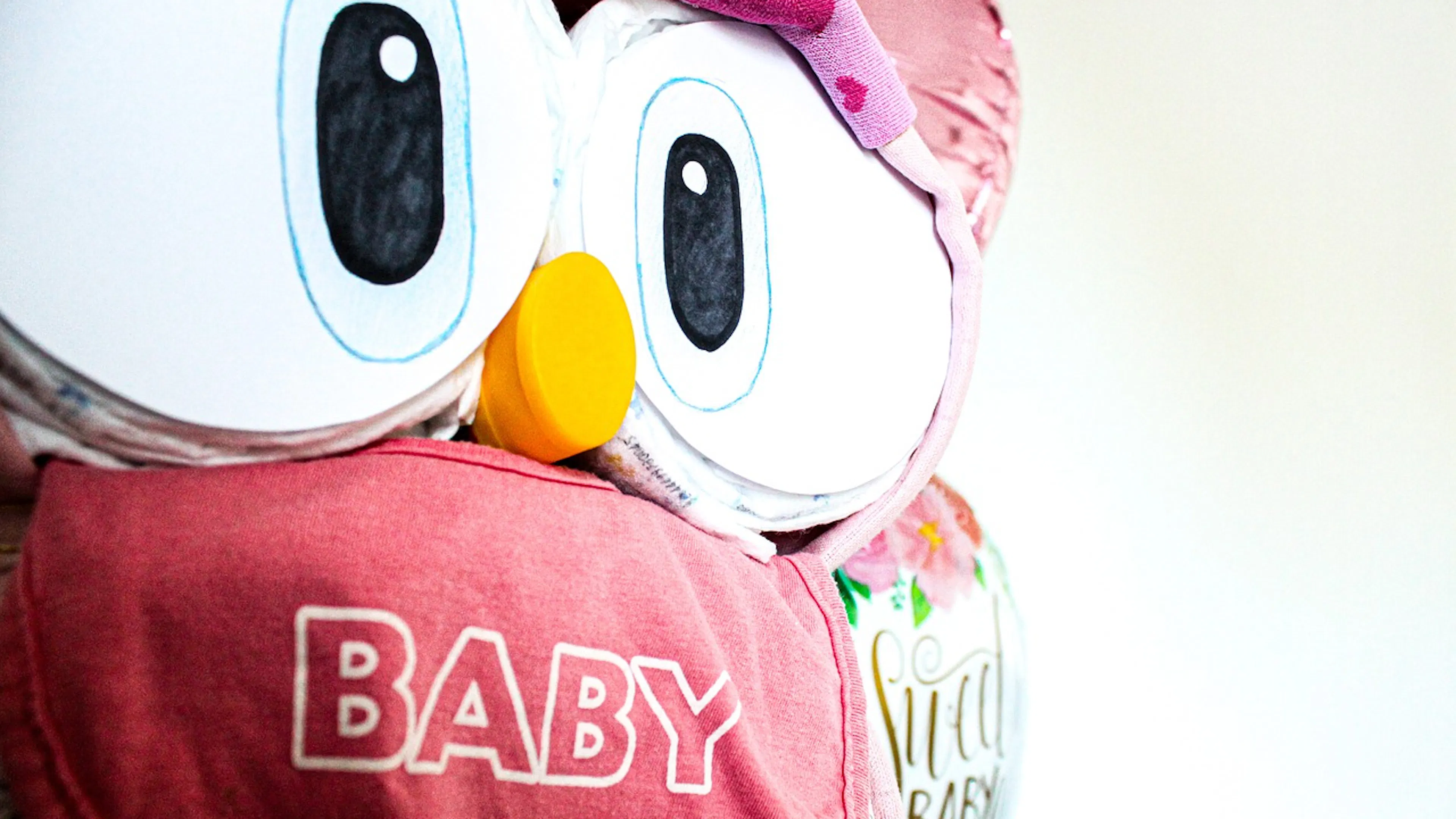 An owl made up of rolled baby diapers and covered in pink blankets 