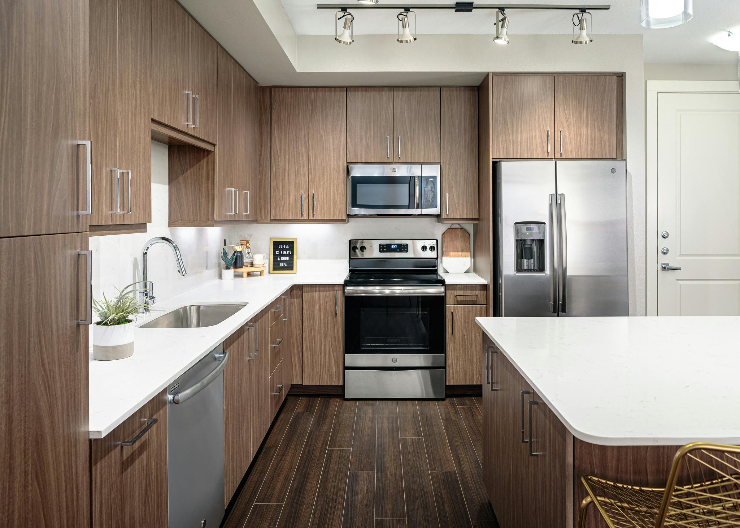 Interior close up of spacious AMLI Addison island kitchen with sleek quartz countertops and light wood cabinets