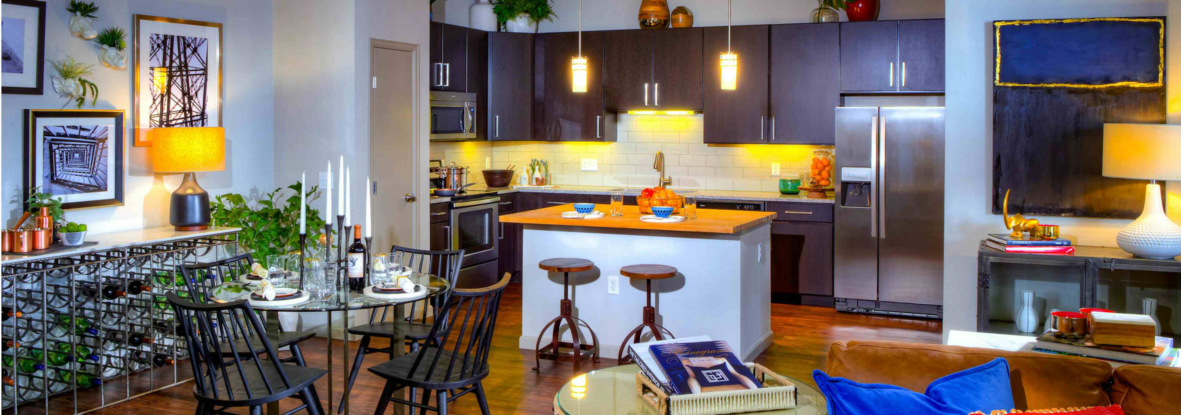 Interior view of a living room and kitchen at AMLI Denargo Market apartments with a dining room table and chairs and lamps