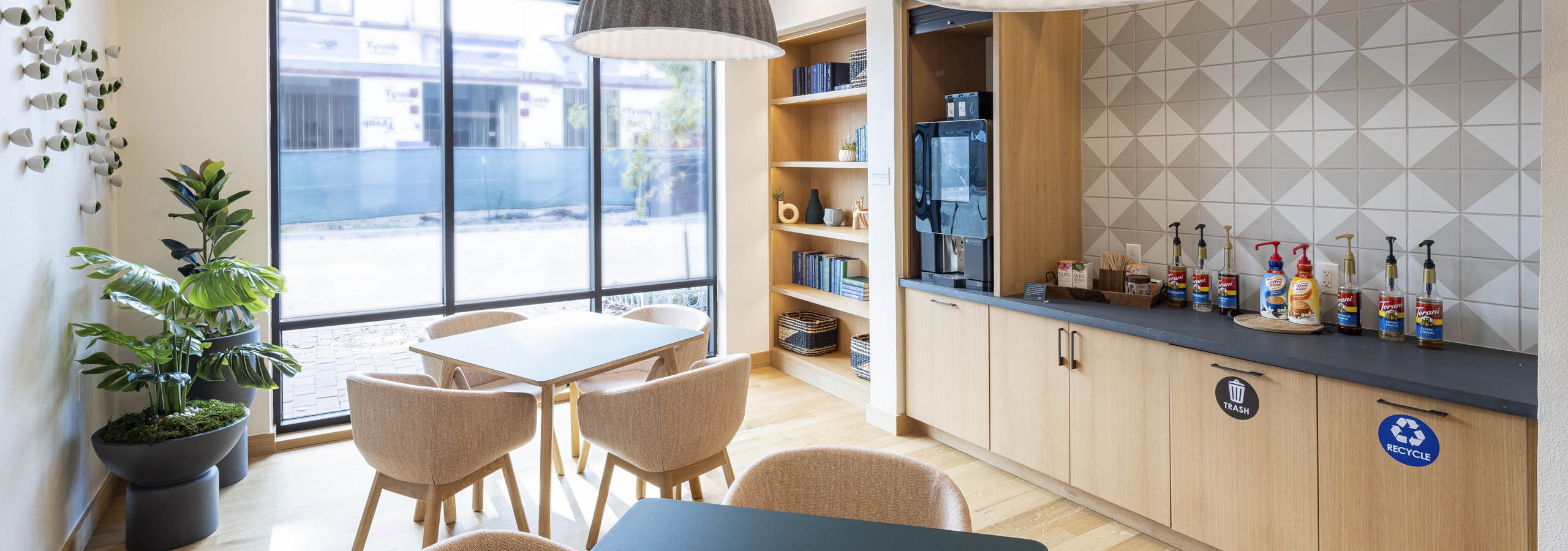 AMLI Branch Park coworking space with featuring tables and chairs and a java bar equipped with coffee creamers and syrups