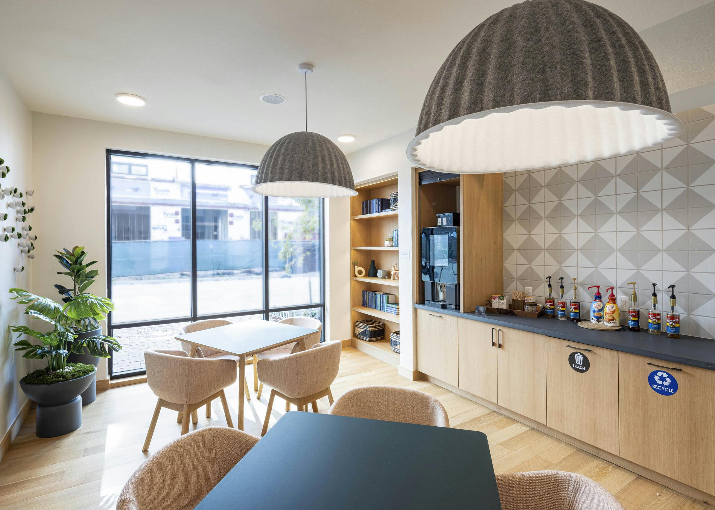 AMLI Branch Park coworking space with featuring tables and chairs and a java bar equipped with coffee creamers and syrups