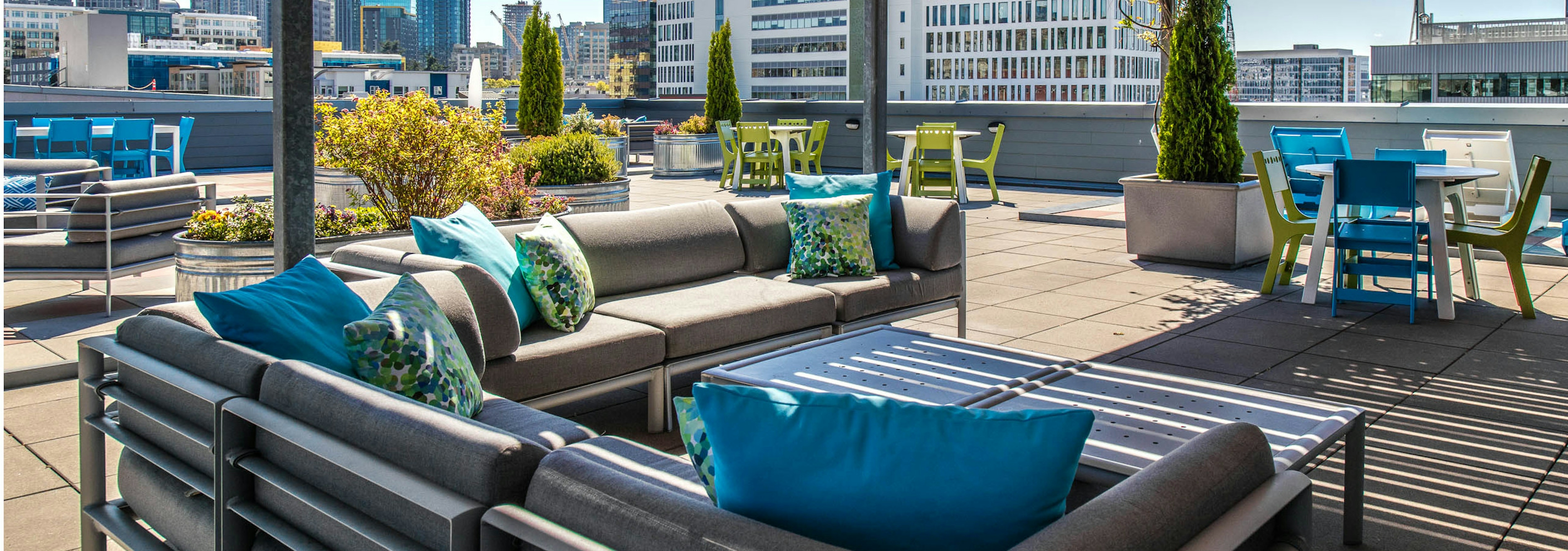 Daytime view of rooftop deck with outdoor patio furniture plants and view of Seattle  