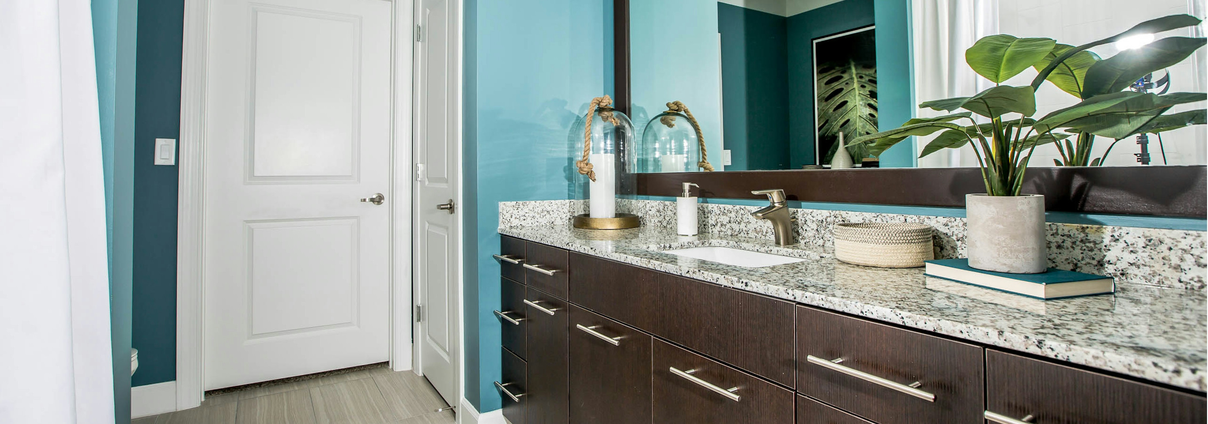 Interior view of a bathroom at AMLI Joya apartment with double sink vanity, large mirror on wall and granite counters