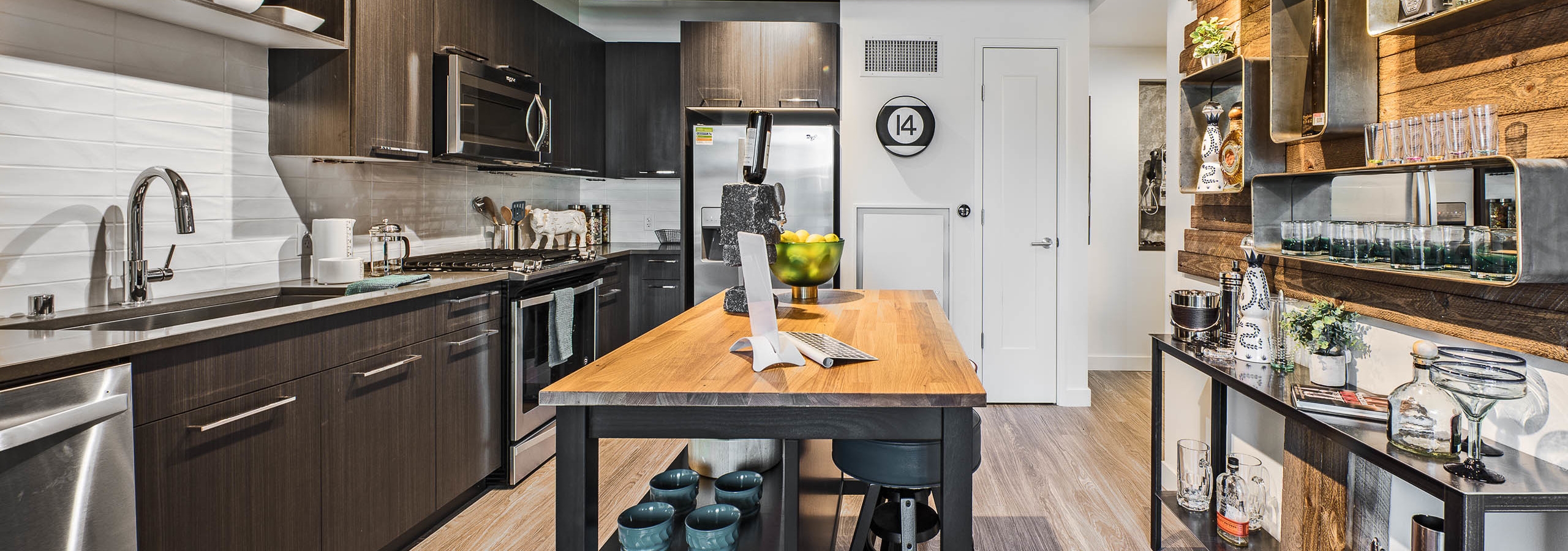 Interior view of apartment of AMLI Arc of kitchen with dark cabinets stainless steel appliances and entry way