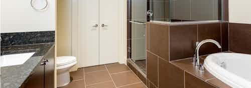 Interior view of AMLI Design District apartment bathroom with granite countertop and oval garden tub with tile surround