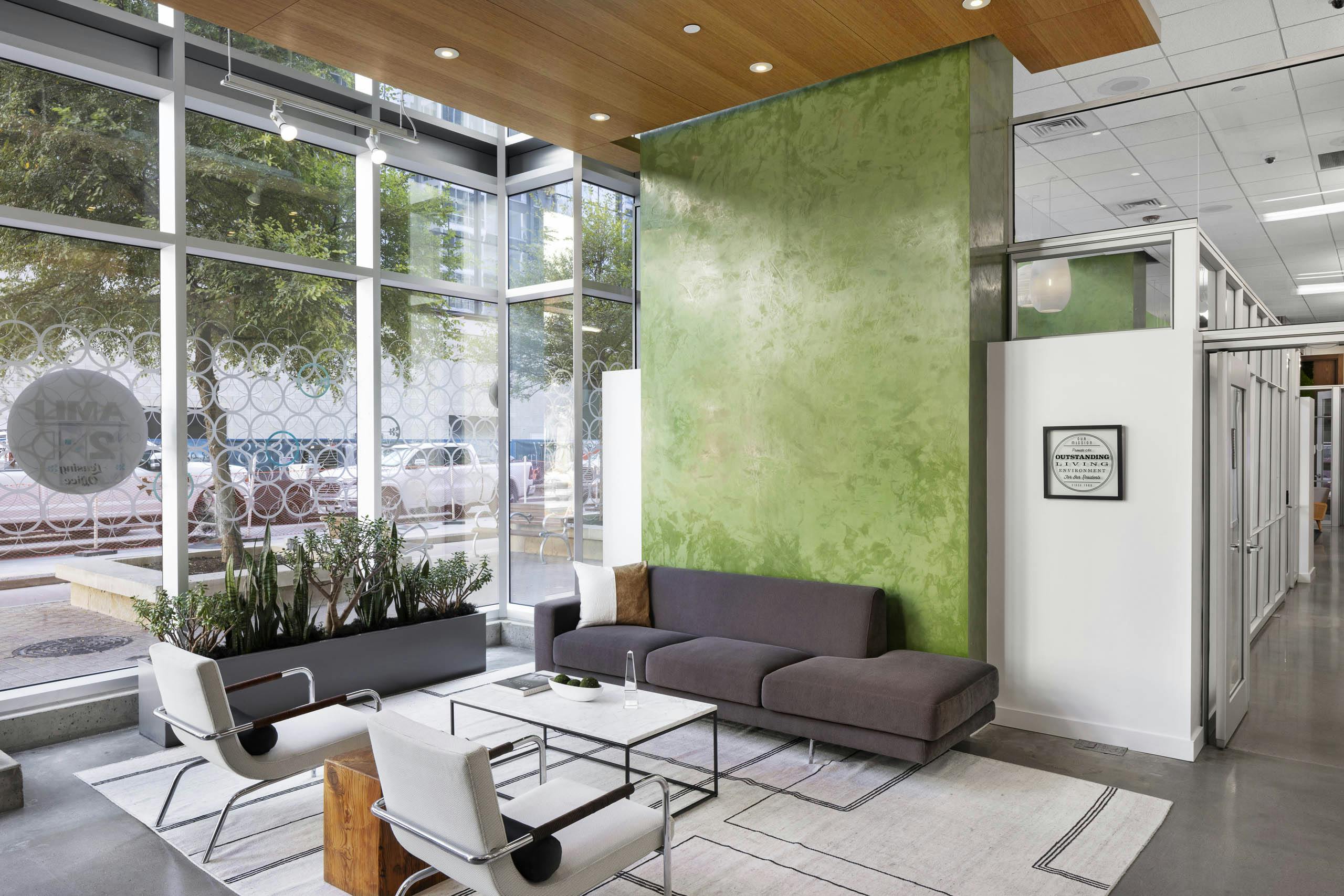AMLI on 2nd lobby with floor to ceiling windows and green wall with gray sofa and 2 white chairs around coffee table