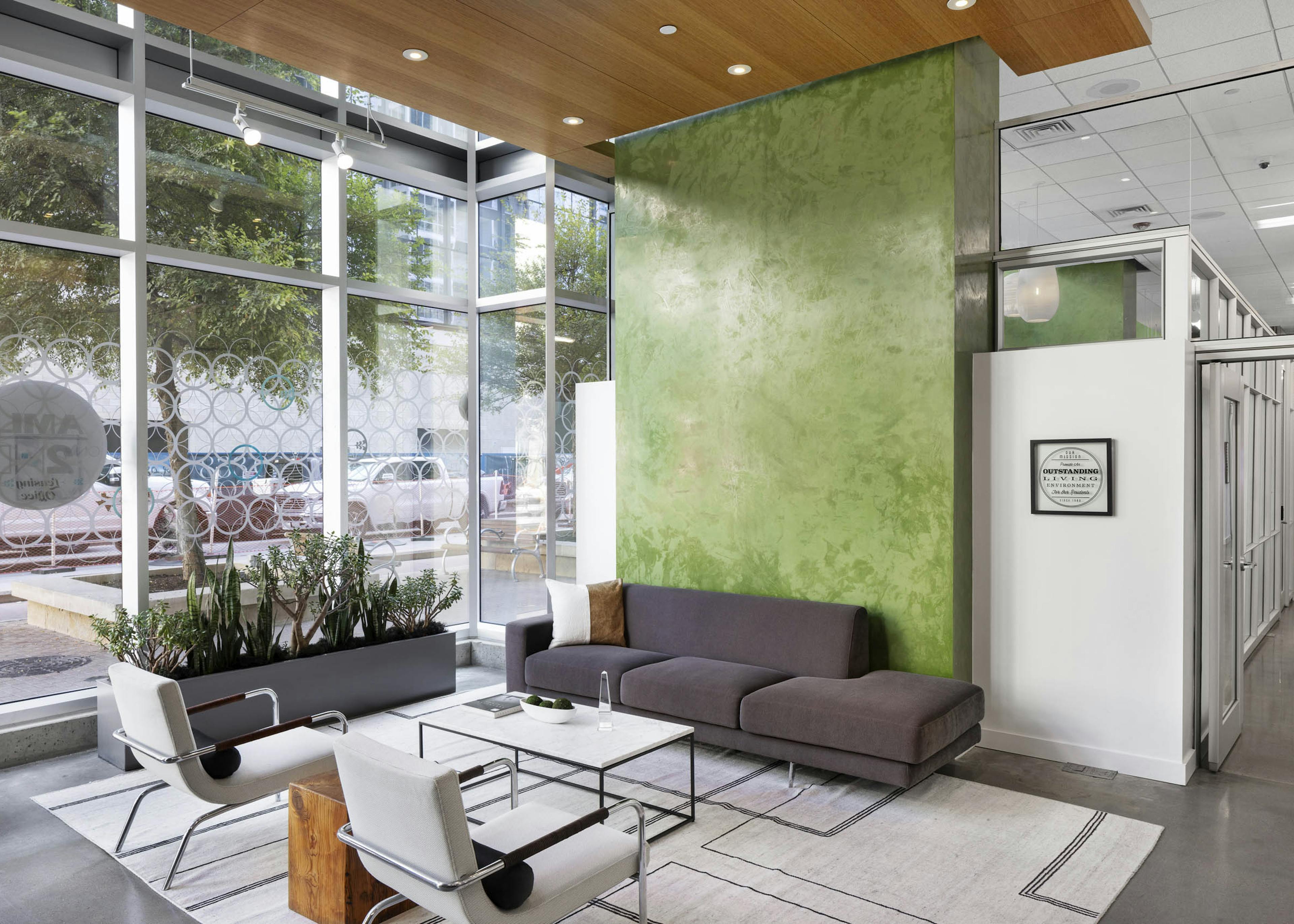 AMLI on 2nd lobby with floor to ceiling windows and green wall with gray sofa and 2 white chairs around coffee table