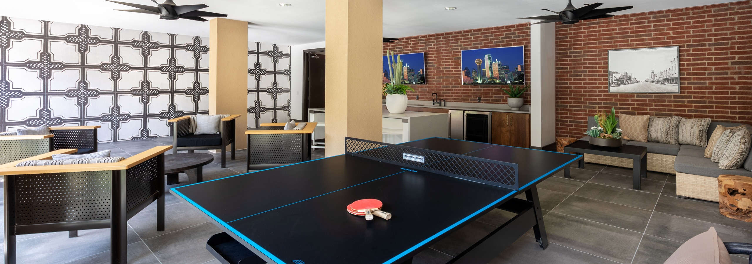 Interior view of AMLI Grapevine resident pool house with lounge seating and black ping pong table with two orange paddles
