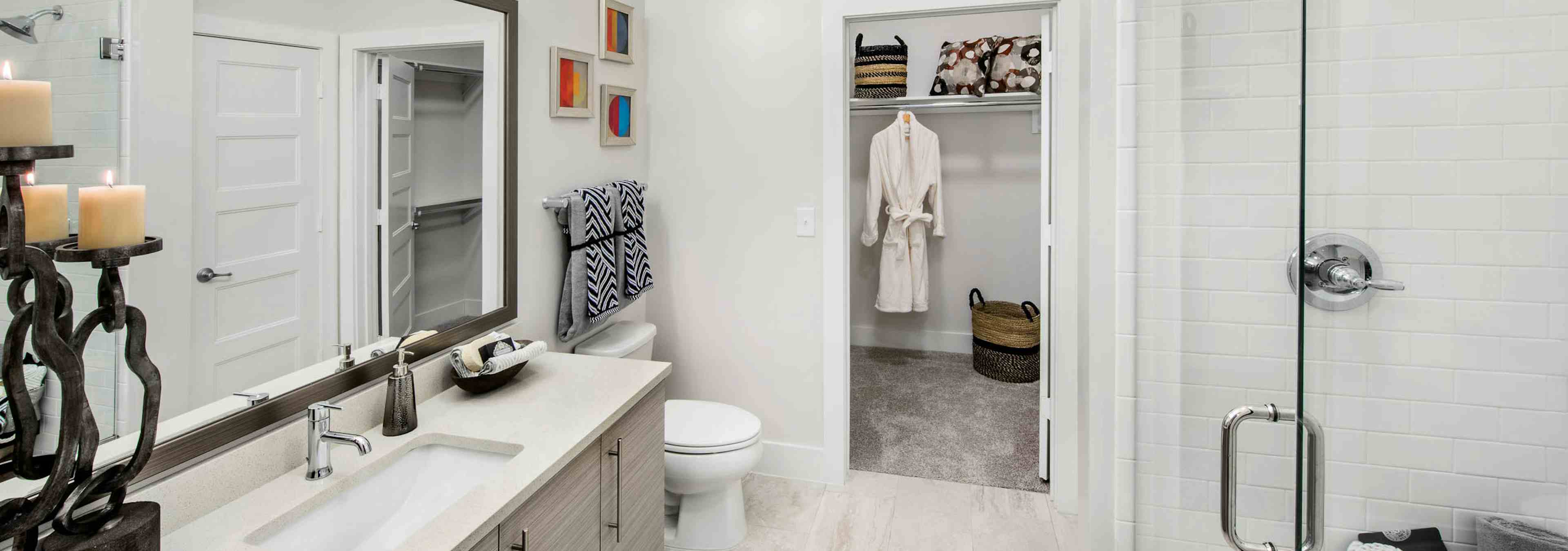 AMLI Buckhead bathroom with a vanity sink and clear glass door leading into the shower with walk in closet door peaking open