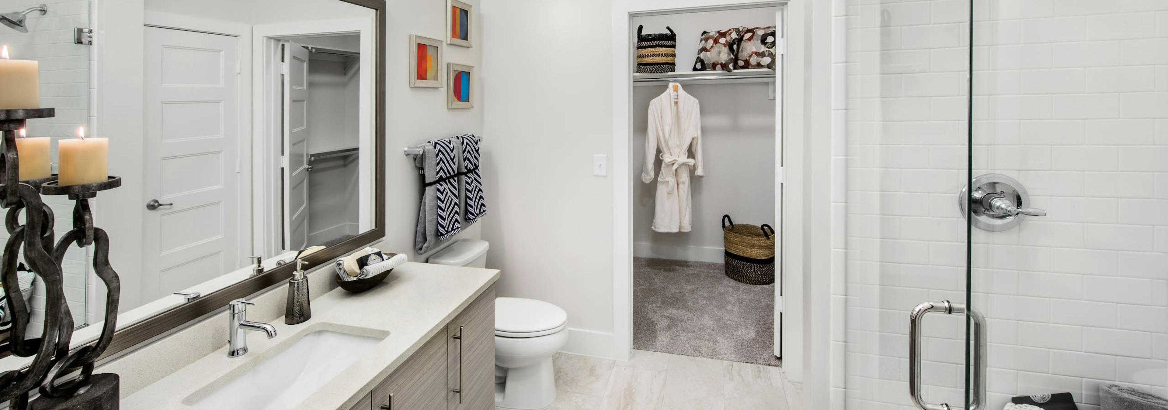 AMLI Buckhead bathroom with a vanity sink and clear glass door leading into the shower with walk in closet door peaking open