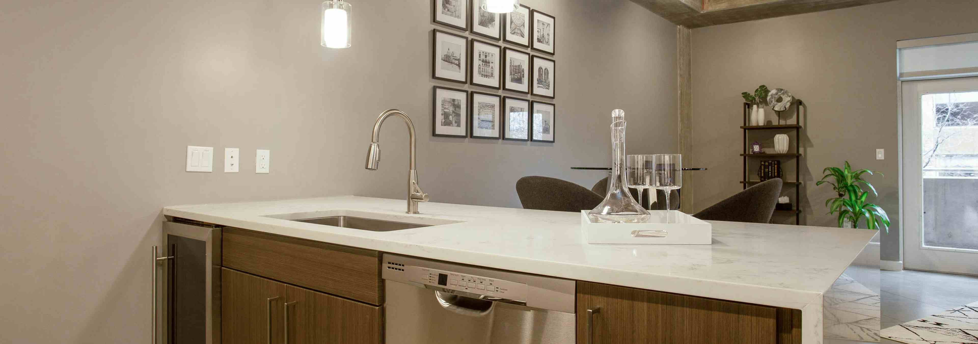 View from behind AMLI Downtown kitchen island with peek into living area with natural light coming in through window