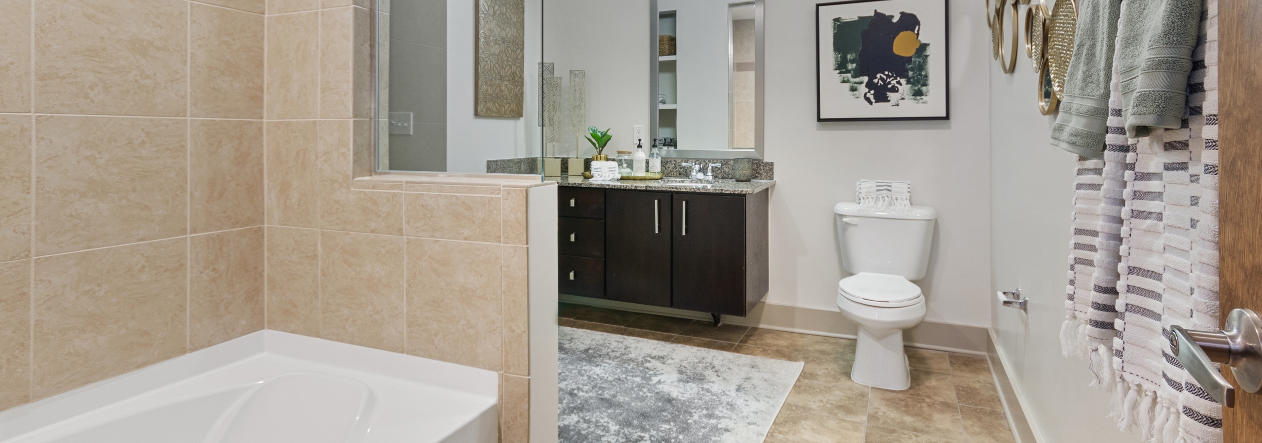 AMLI Old 4th Ward apartment bathroom with granite countertops and dark cabinets with a garden tub and light tile flooring
