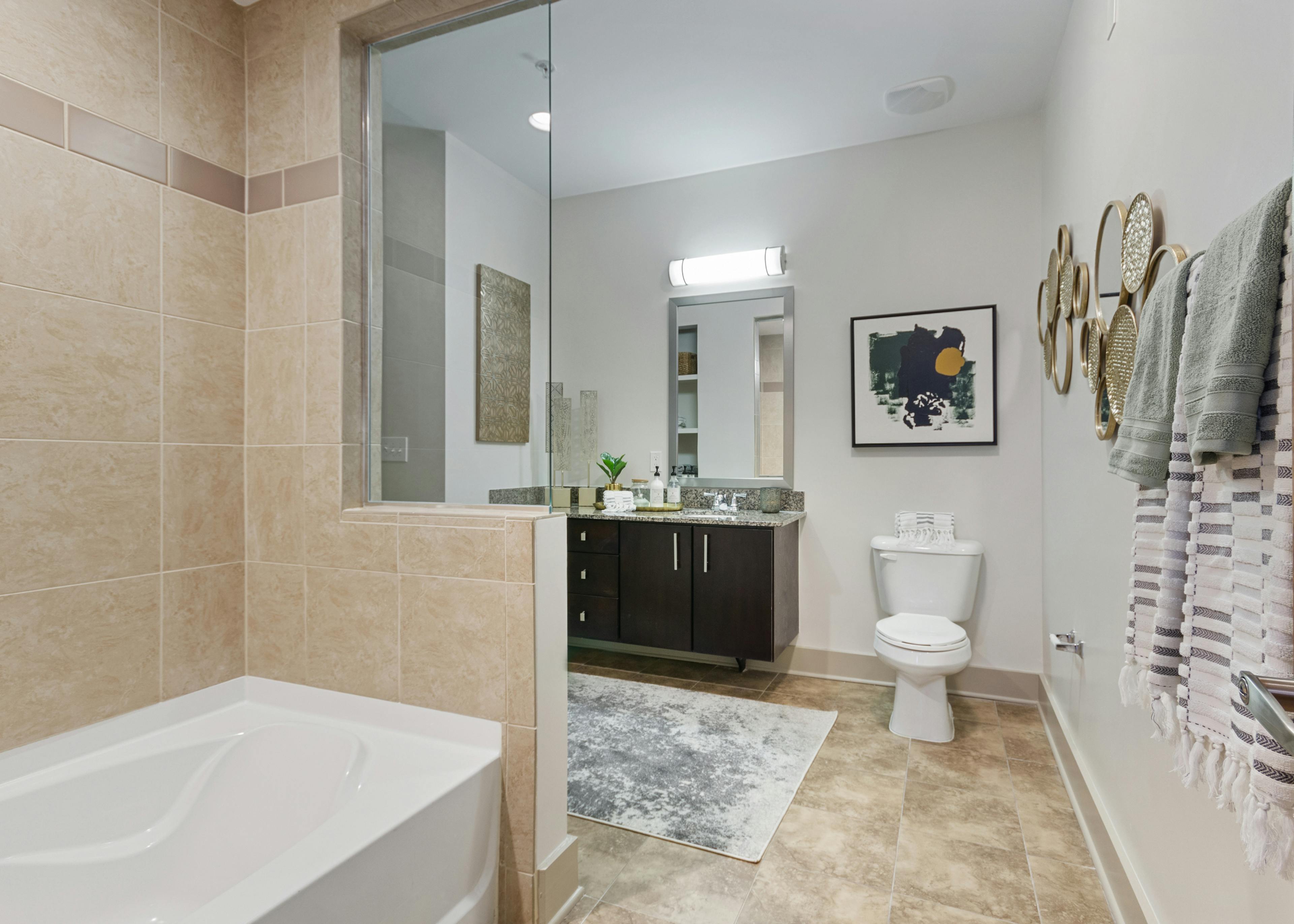 AMLI Old 4th Ward apartment bathroom with granite countertops and dark cabinets with a garden tub and light tile flooring
