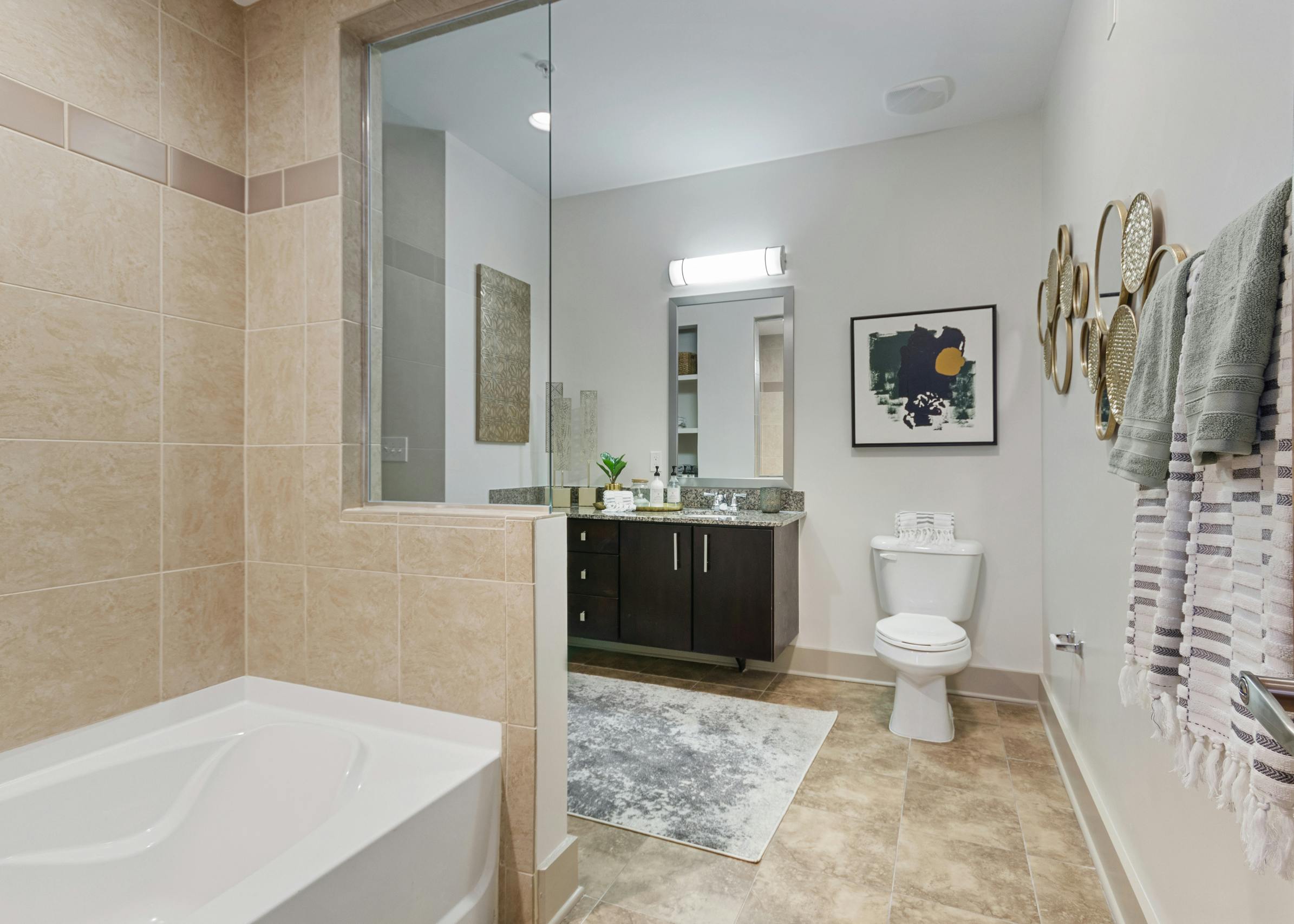 AMLI Old 4th Ward apartment bathroom with granite countertops and dark cabinets with a garden tub and light tile flooring
