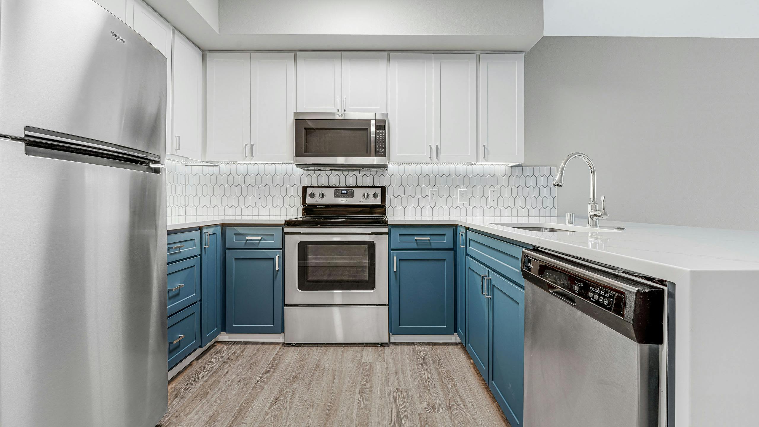 Kitchen at AMLI 535 apartment building with white and blue cabinets and stainless steel appliances with light gray floors