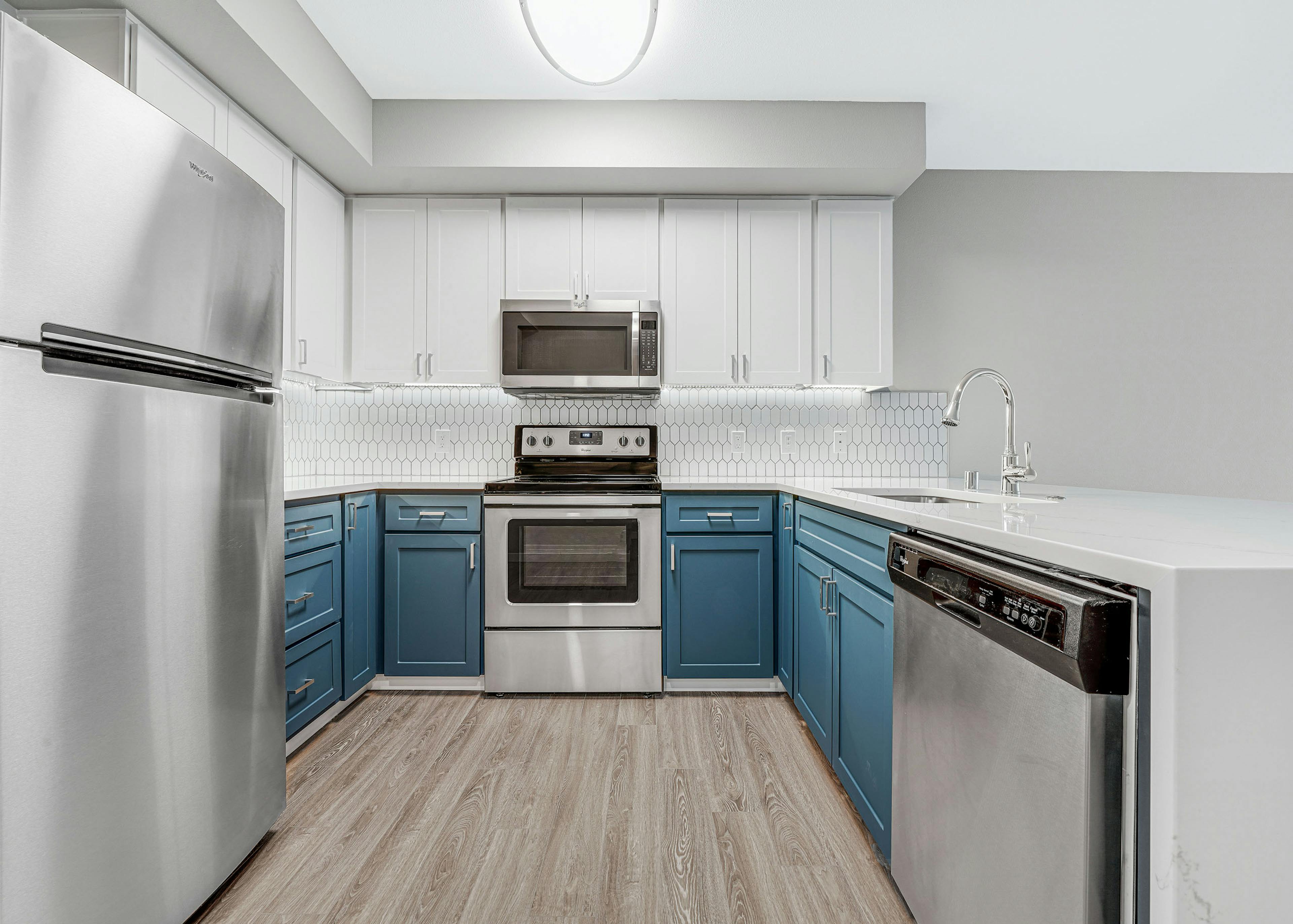 Kitchen at AMLI 535 apartment building with white and blue cabinets and stainless steel appliances with light gray floors